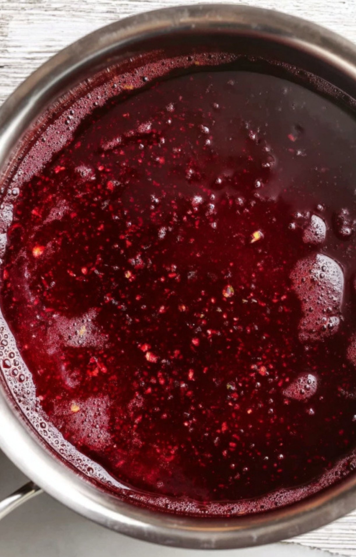 Red wine sauce bubbling in a pot, full of deep savory flavor for pairing with beef wellington, steak, or roast beef.