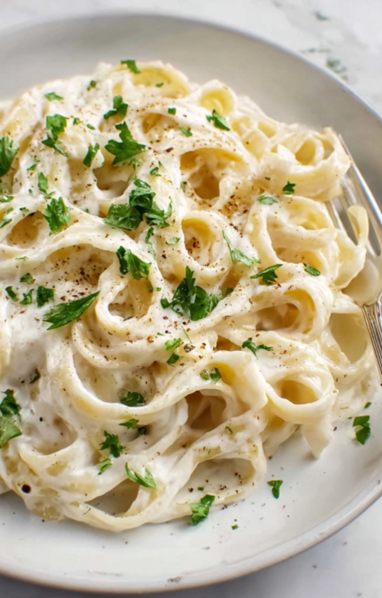 Plate of creamy cauliflower Alfredo fettuccine with fresh herbs, a cozy comfort food option for busy nights.