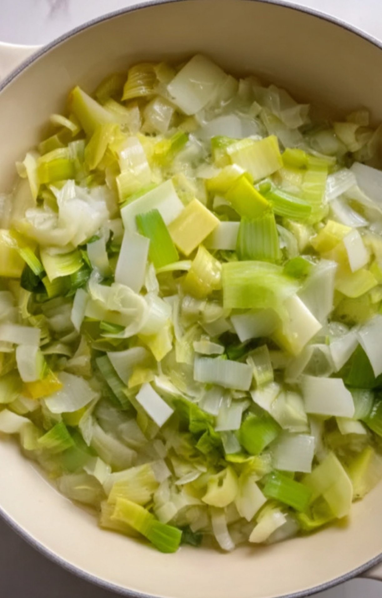 A pan of freshly sautéed leeks and onions, the perfect aromatic base for making French spring soup. Simple, healthy, and full of flavor for homemade soups.