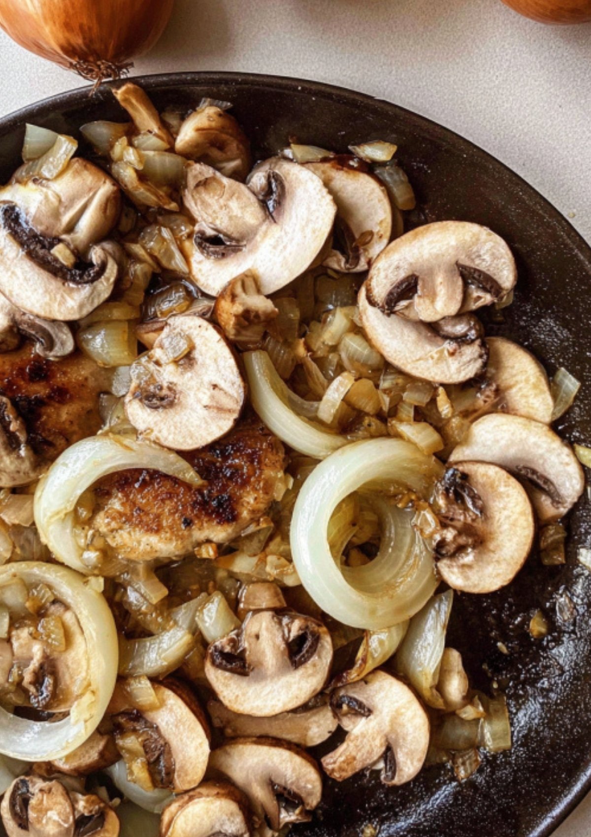 Caramelized onions and fresh mushrooms cooking in a pan for chop steak gravy.