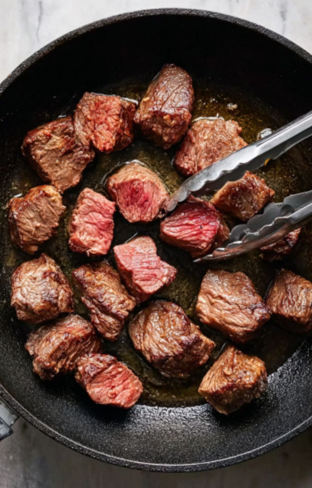 Cubes of beef being browned in a cast iron skillet, showing the first step for hearty goulash stew.