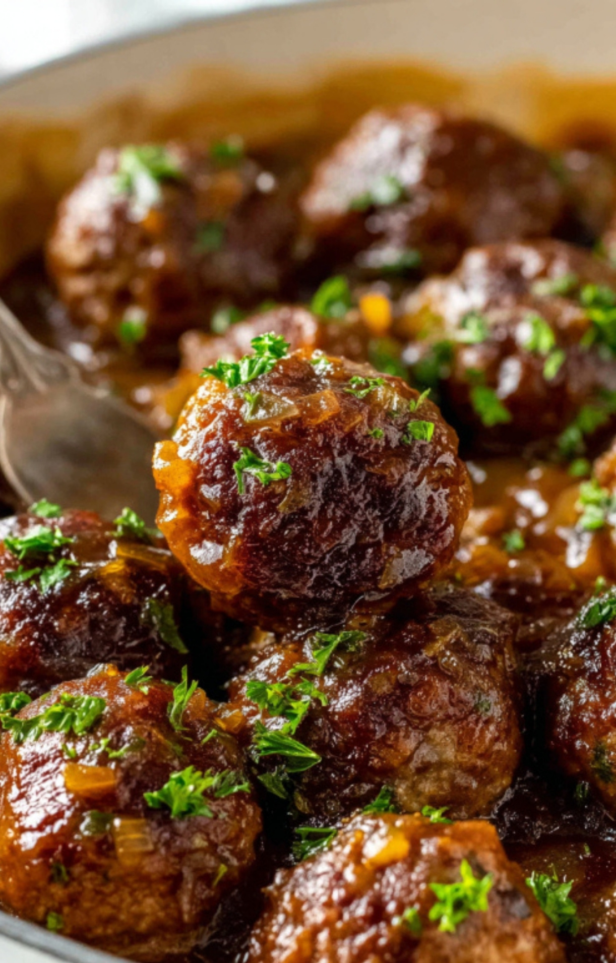Fork lifting juicy Salisbury Steak Meatball from skillet with homemade onion gravy.
