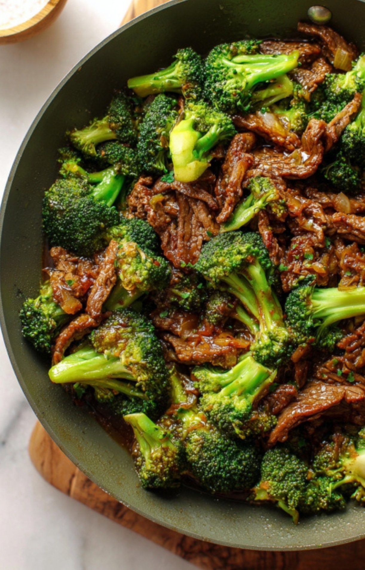 Closeup of a skillet filled with glossy shaved beef, crisp-tender broccoli, and a rich homemade stir fry sauce, ideal for easy Asian-inspired dinners.