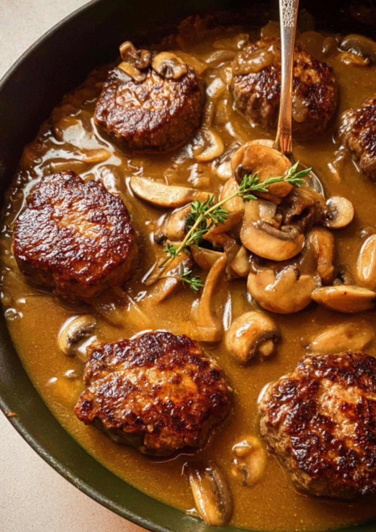 Seared beef patties simmering in rich mushroom and onion gravy for classic comfort food.