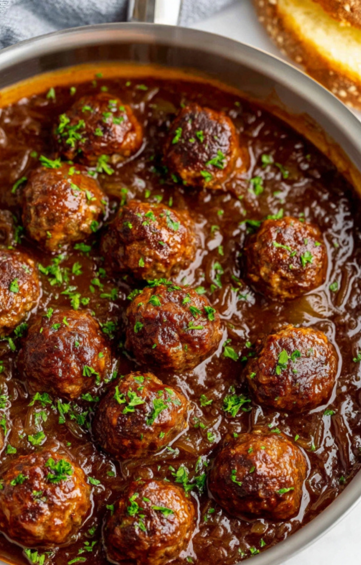 Close-up of Salisbury Steak Meatballs in skillet with rich brown gravy, topped with fresh parsley.