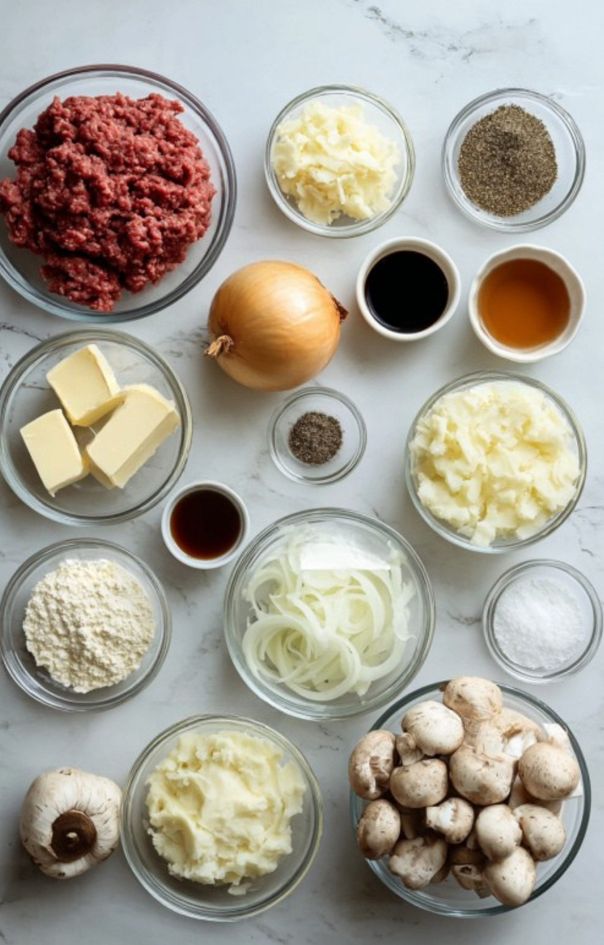Overhead shot of ingredients for Salisbury Steak Casserole including ground beef, mushrooms, onions, butter, flour, mashed potatoes, and seasonings. Perfect for cozy family dinners and easy weeknight meals.