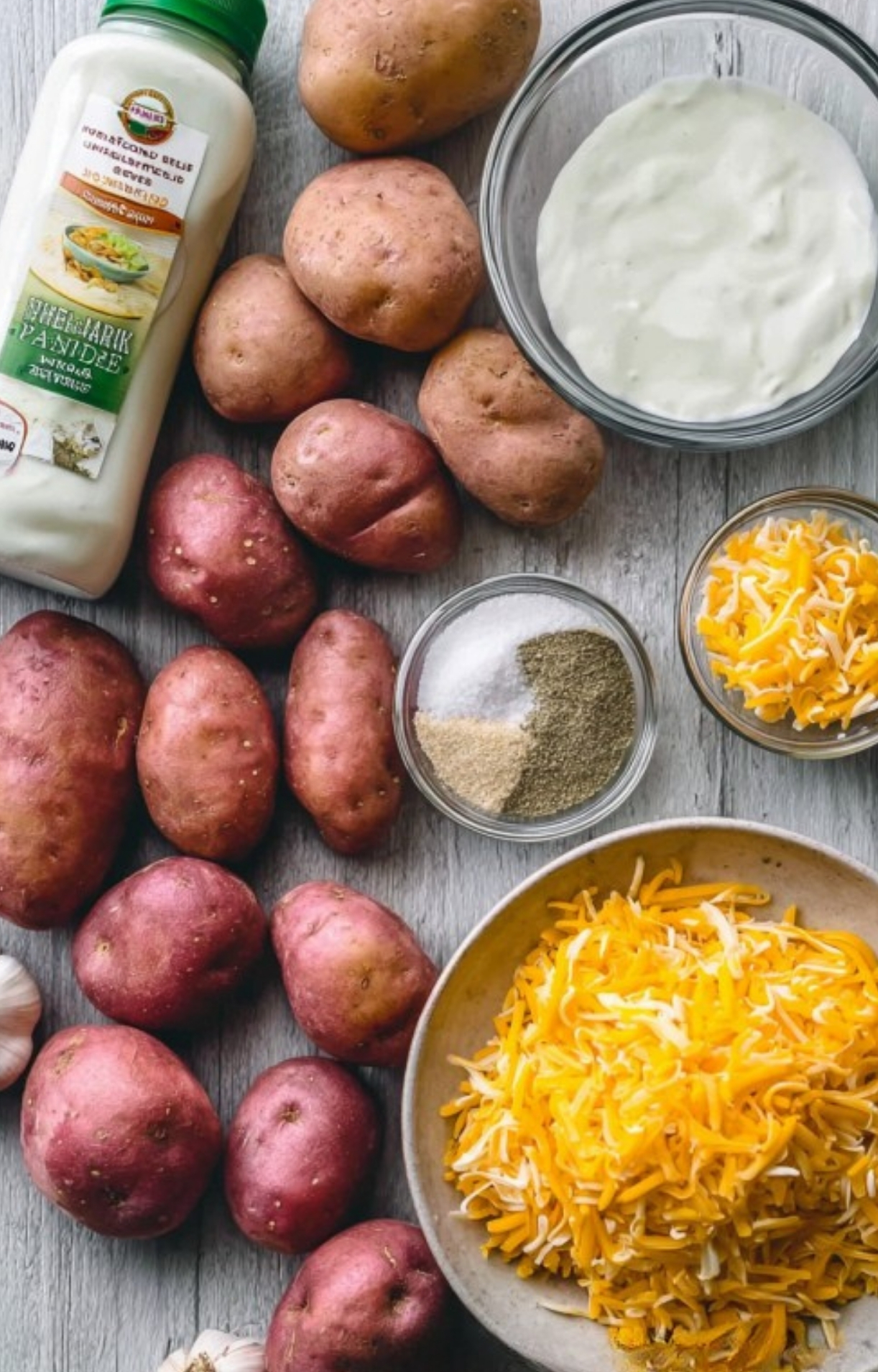 Flat lay of baby red potatoes, ranch dressing, shredded cheese, and seasonings for making quick cheesy ranch potatoes, ideal for weeknight meals.