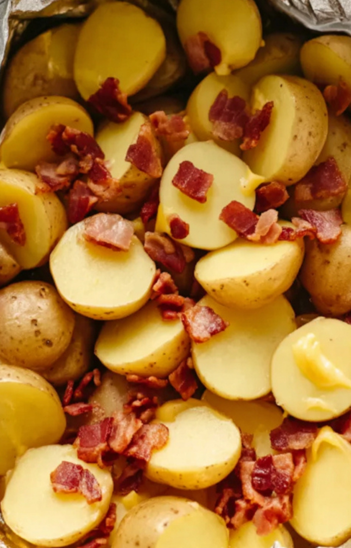 Sliced baby potatoes and crispy bacon pieces in foil, prepped for slow cooker cheesy bacon ranch potatoes, a simple comfort food recipe.