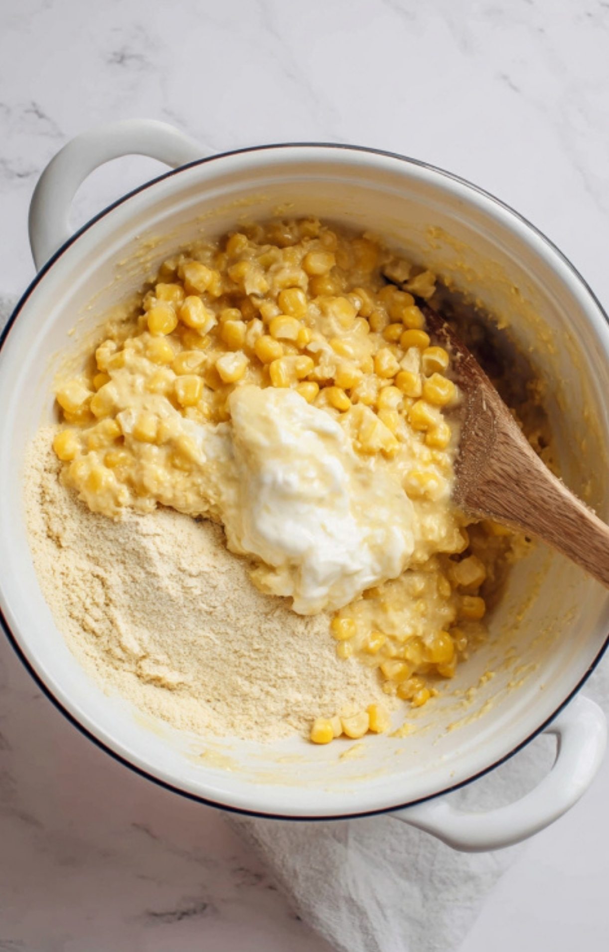 Corn, sour cream, and Jiffy mix being combined for a cheesy Southern corn casserole recipe
