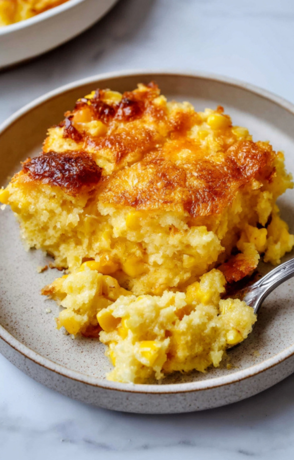 A warm, golden slice of Corn Bake Casserole Jiffy on a plate, showing its moist texture and sweet-savory flavor, perfect as a cozy side for any meal or holiday dinner.