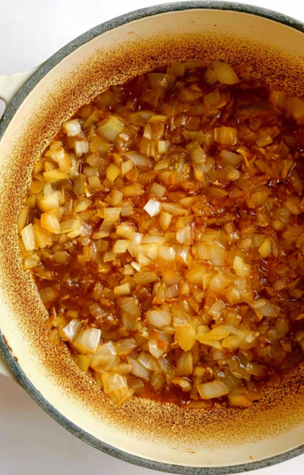 Finely diced onions being sautéed until translucent and golden in a large pot, the first step in a classic Hungarian Goulash Recipe.