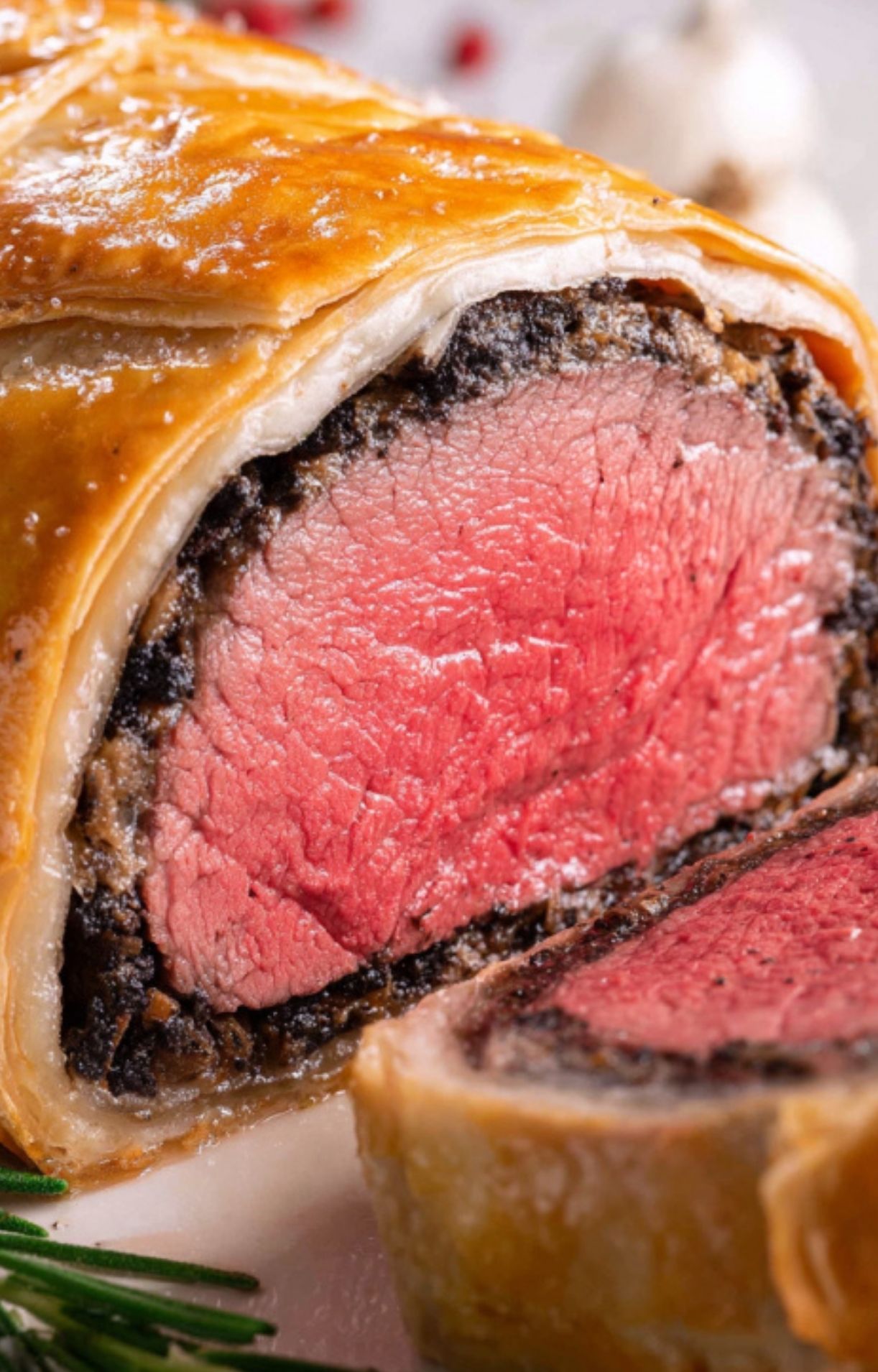 A closeup of a sliced gluten free beef wellington showing a golden flaky crust and juicy tender beef, great for holiday meals and special occasions.