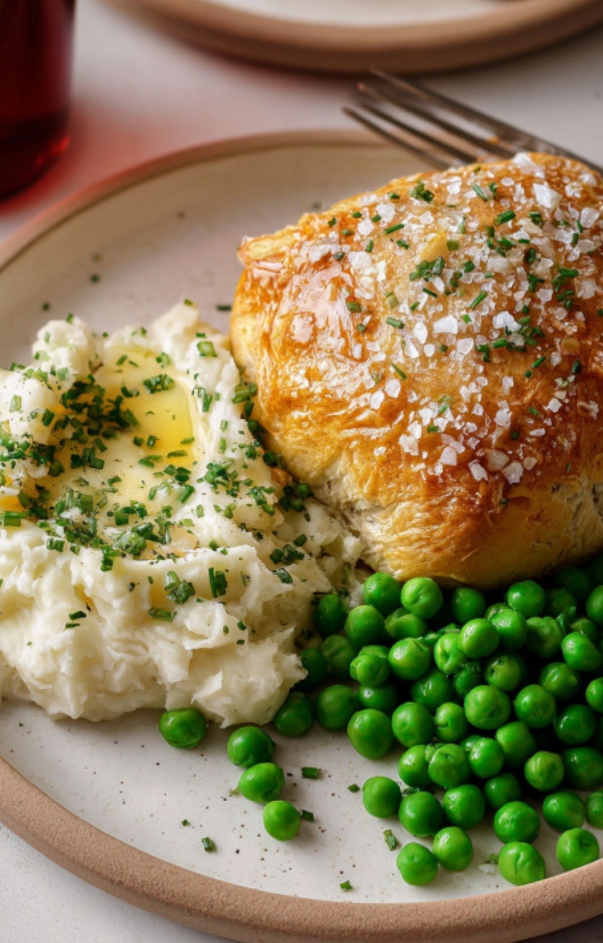 Golden baked mini beef Wellington served with fluffy mashed potatoes and bright green peas, sprinkled with fresh chives for a cozy holiday dinner.