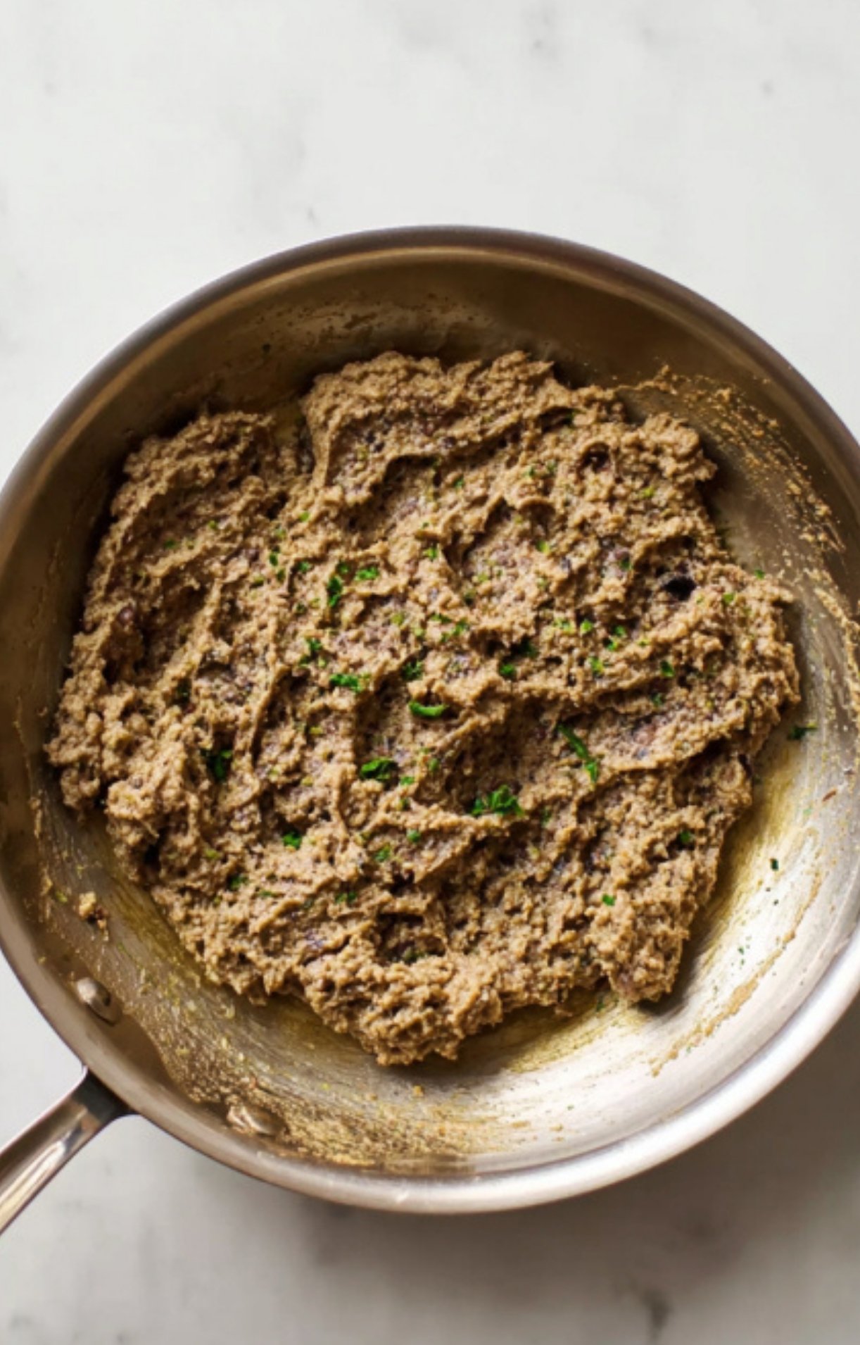 A skillet filled with cooked mushroom duxelles, a rich and flavorful filling used in classic beef wellington. Step-by-step holiday recipe for making the best wellington at home.