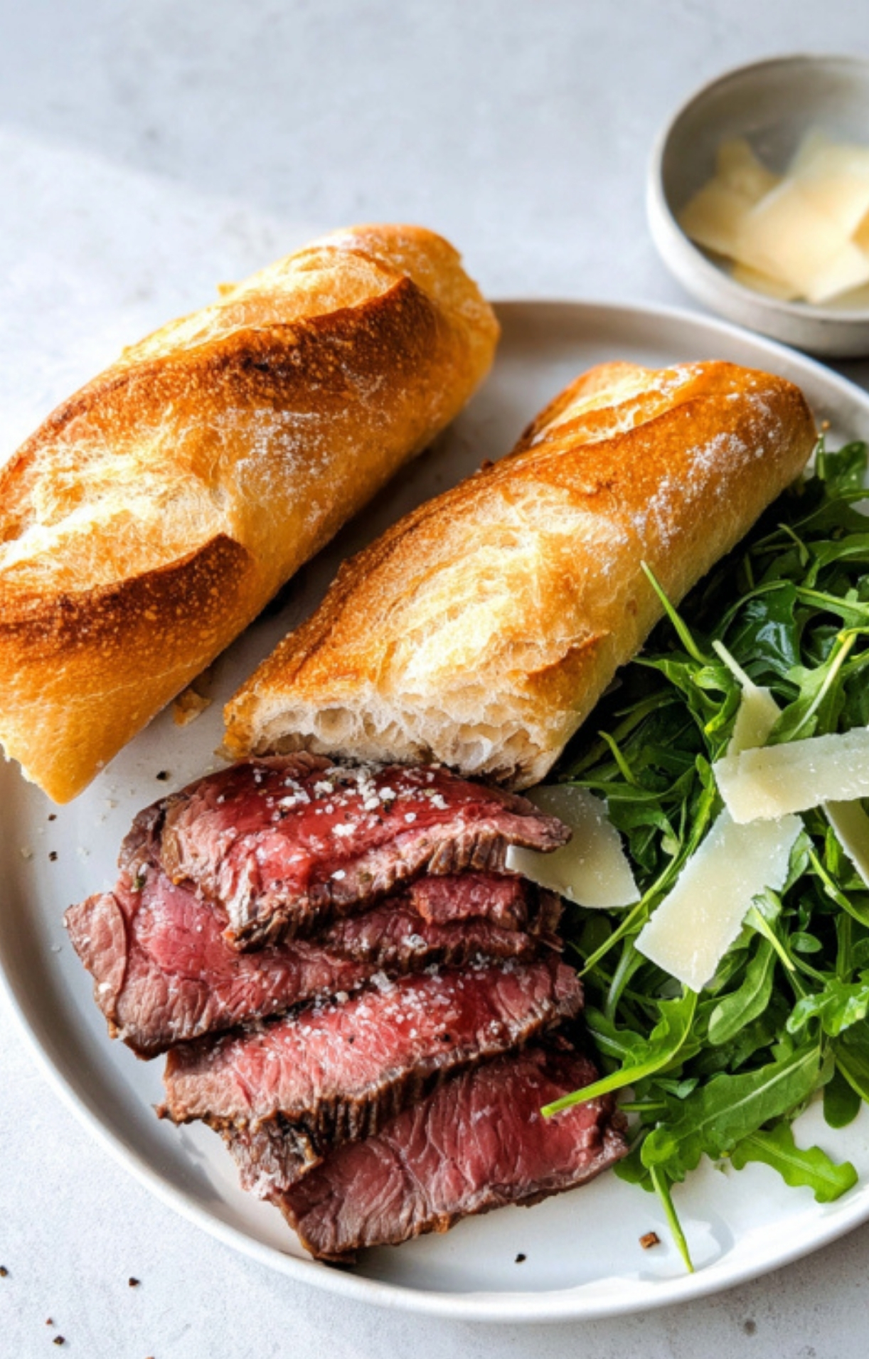 Close-up of shaved beef, arugula, and parmesan piled inside a crispy baguette, highlighting an easy, flavorful lunch sandwich.
