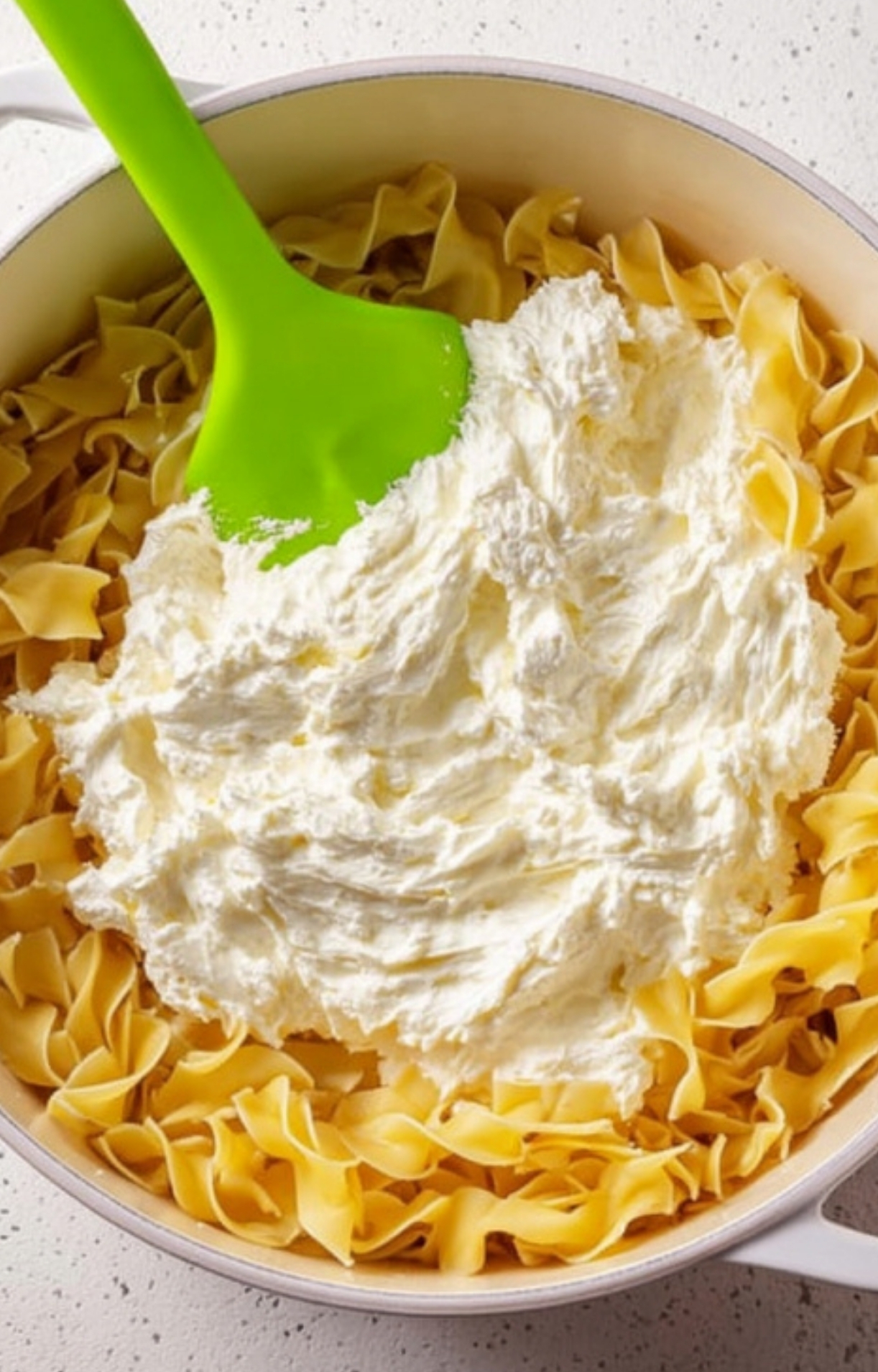 Mixing cooked egg noodles with rich cream cheese and sour cream for the ultimate creamy casserole base, ideal for busy weeknights.