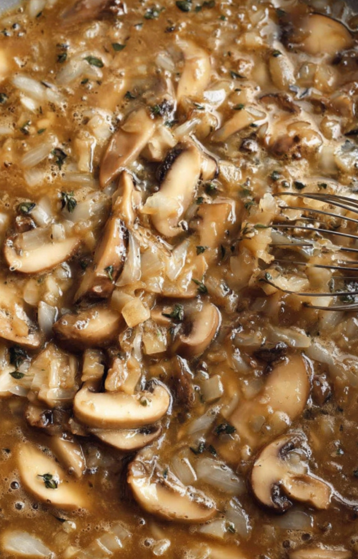 Rich mushroom and onion gravy bubbling in a skillet, ready to combine with beef for a flavorful casserole base.