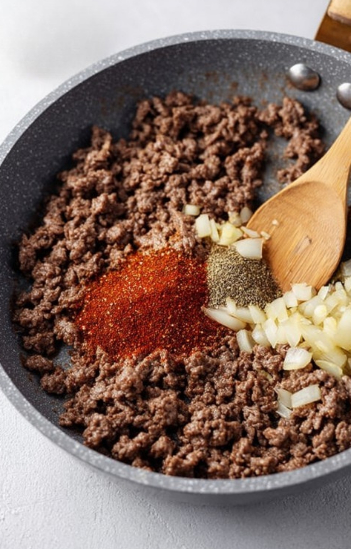 Ground beef browning in a skillet with onions and spices, the first step for making a hearty, classic casserole recipe for dinner.