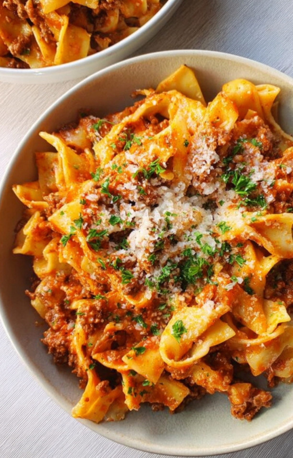 Overhead view of a bowl filled with cheesy noodle casserole topped with ground beef, Parmesan, and herbs—perfect for quick comfort food.