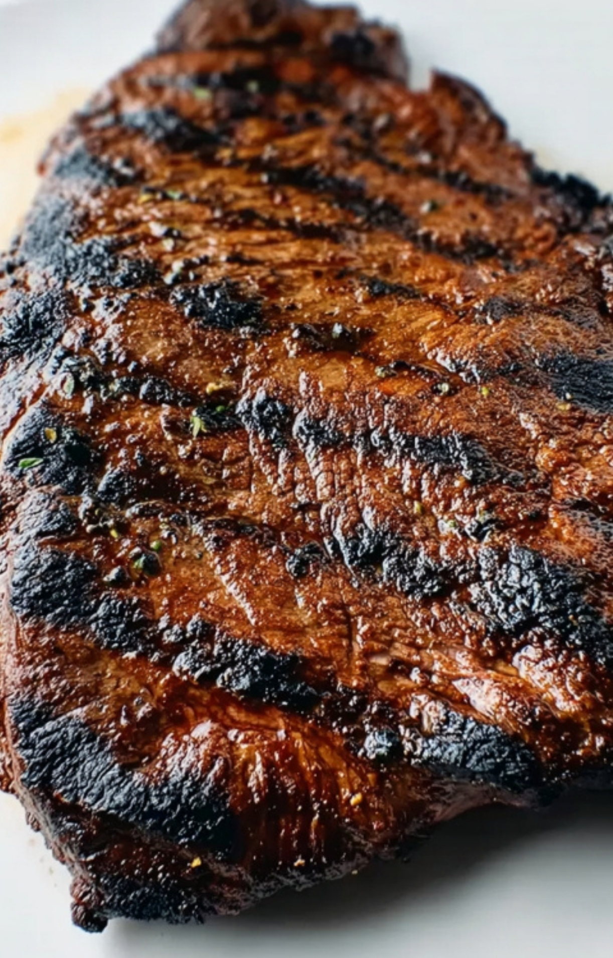 Perfectly grilled flank steak with seared marks, ready for slicing and serving at a family dinner.