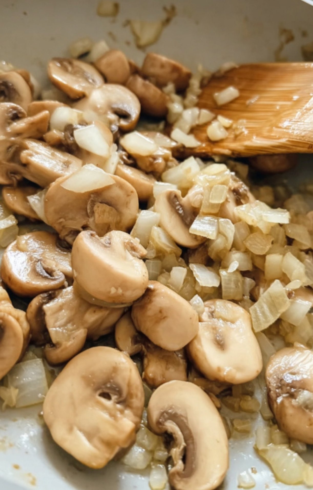 Mushrooms and diced onions sautéing in a skillet as the base for Salisbury steak mushroom gravy.