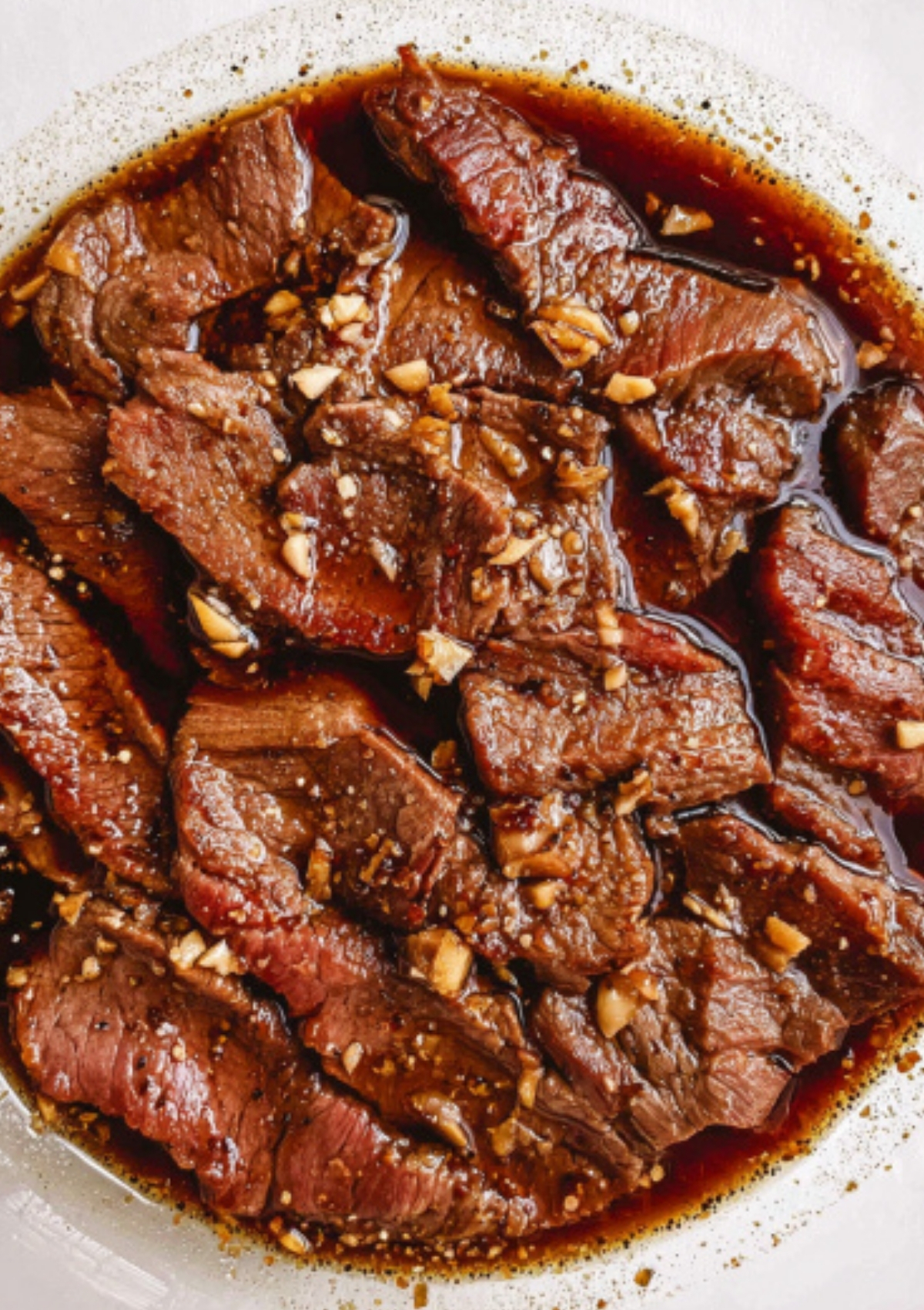 Thin beef slices marinating in soy sauce, garlic, and lemon for Beef Steak Filipino.