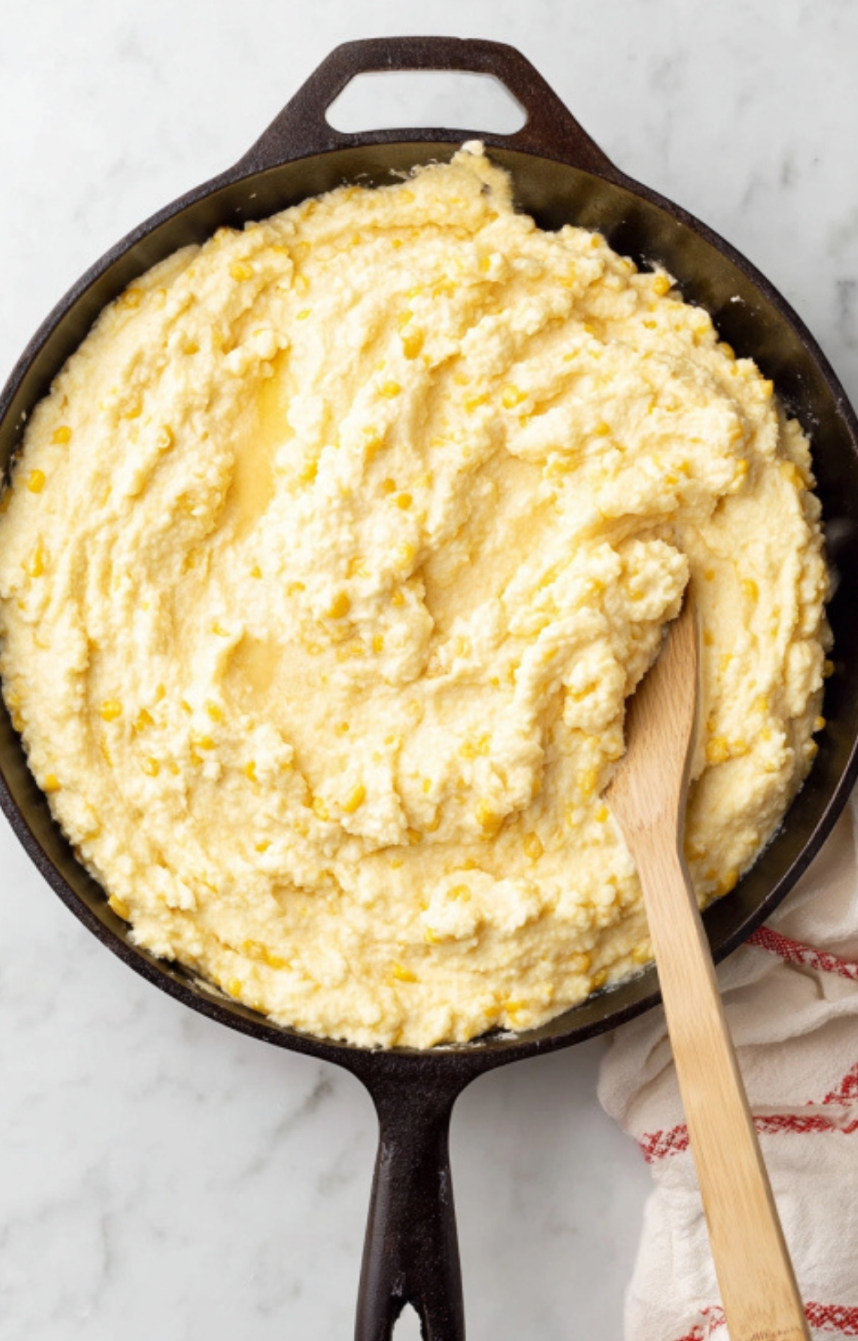 Mixing creamy corn casserole batter in a cast iron skillet for an easy Paula Deen-inspired holiday side dish