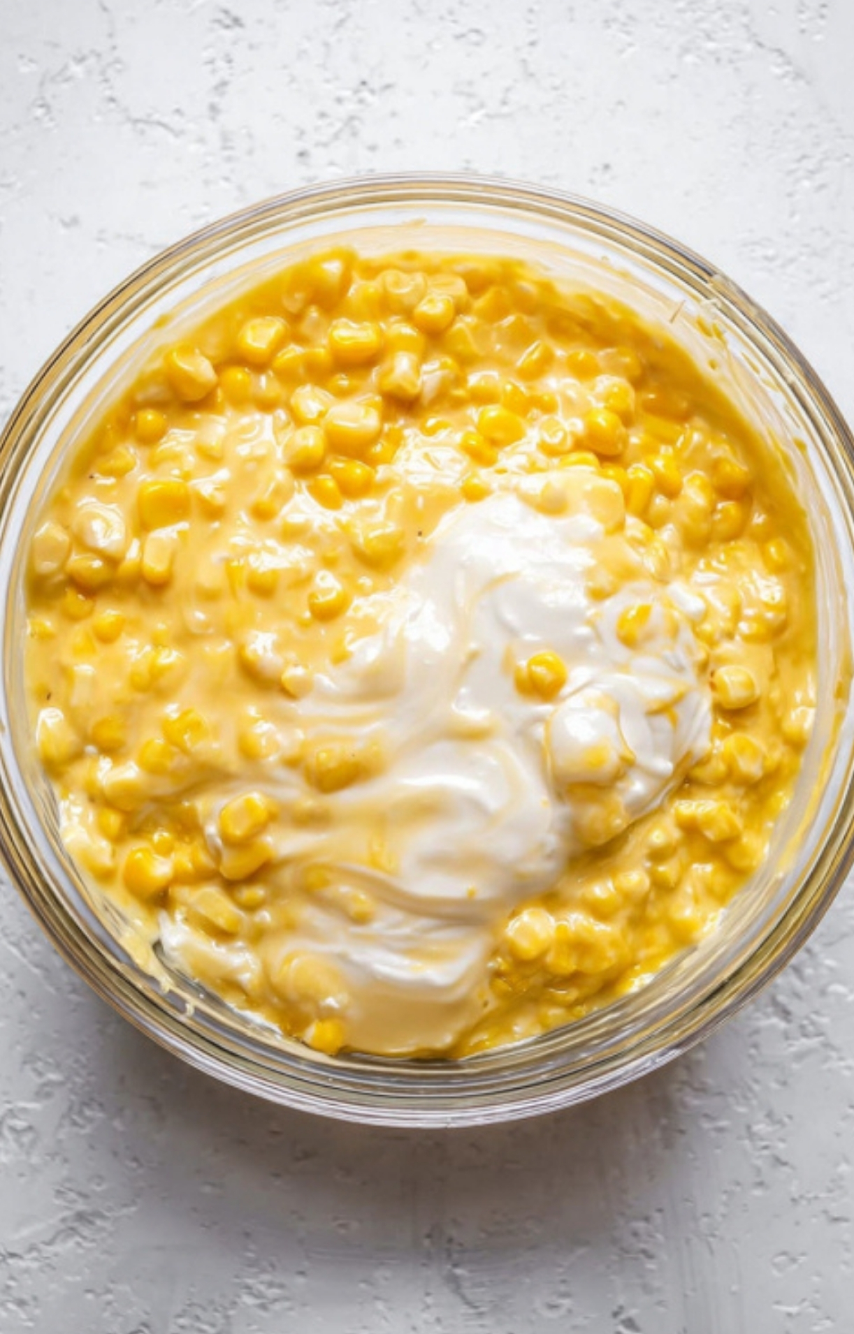 Close-up of sweet corn, sour cream, and creamed corn being mixed for a classic Corn Bake Casserole Jiffy, showing the creamy texture that makes this dish a potluck favorite.