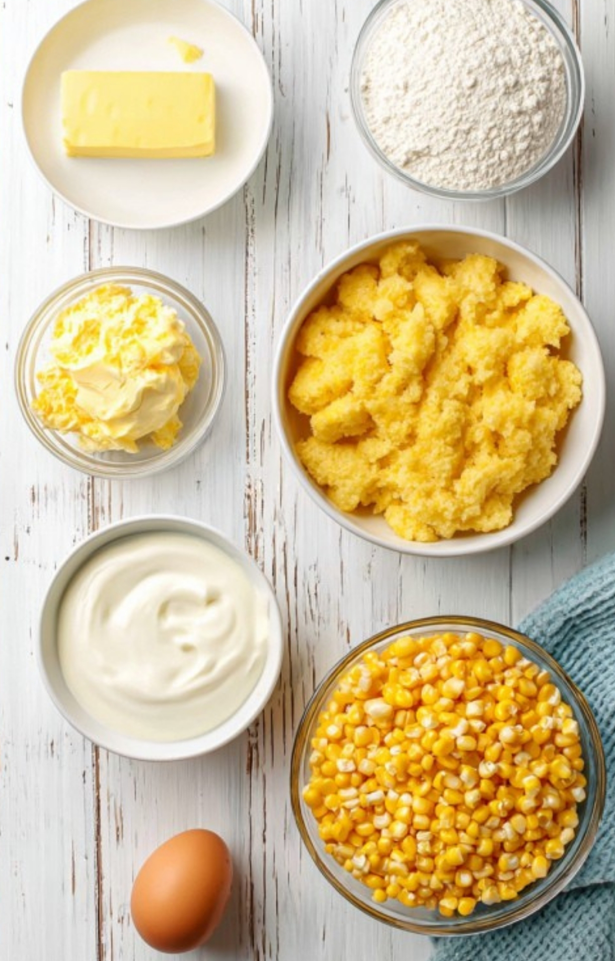 All ingredients for Corn Casserole Jiffy Easy—Jiffy mix, corn, creamed corn, butter, sour cream, flour, and egg—arranged on a rustic wood table for an easy prep side.