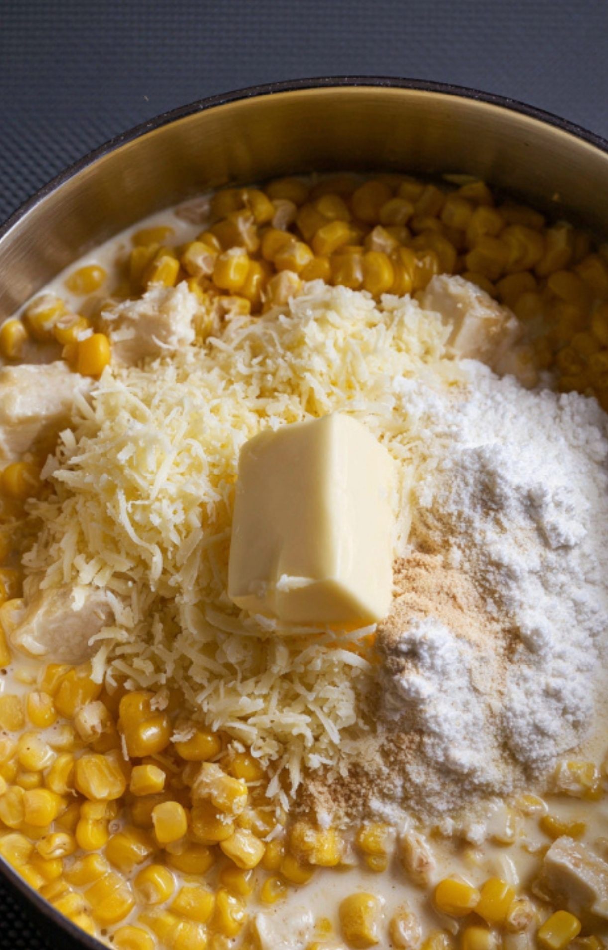 Ingredients for canned cream corn: sweet corn, butter, Parmesan, flour, and cream in a pot, ready to stir together for a quick and classic Southern side.