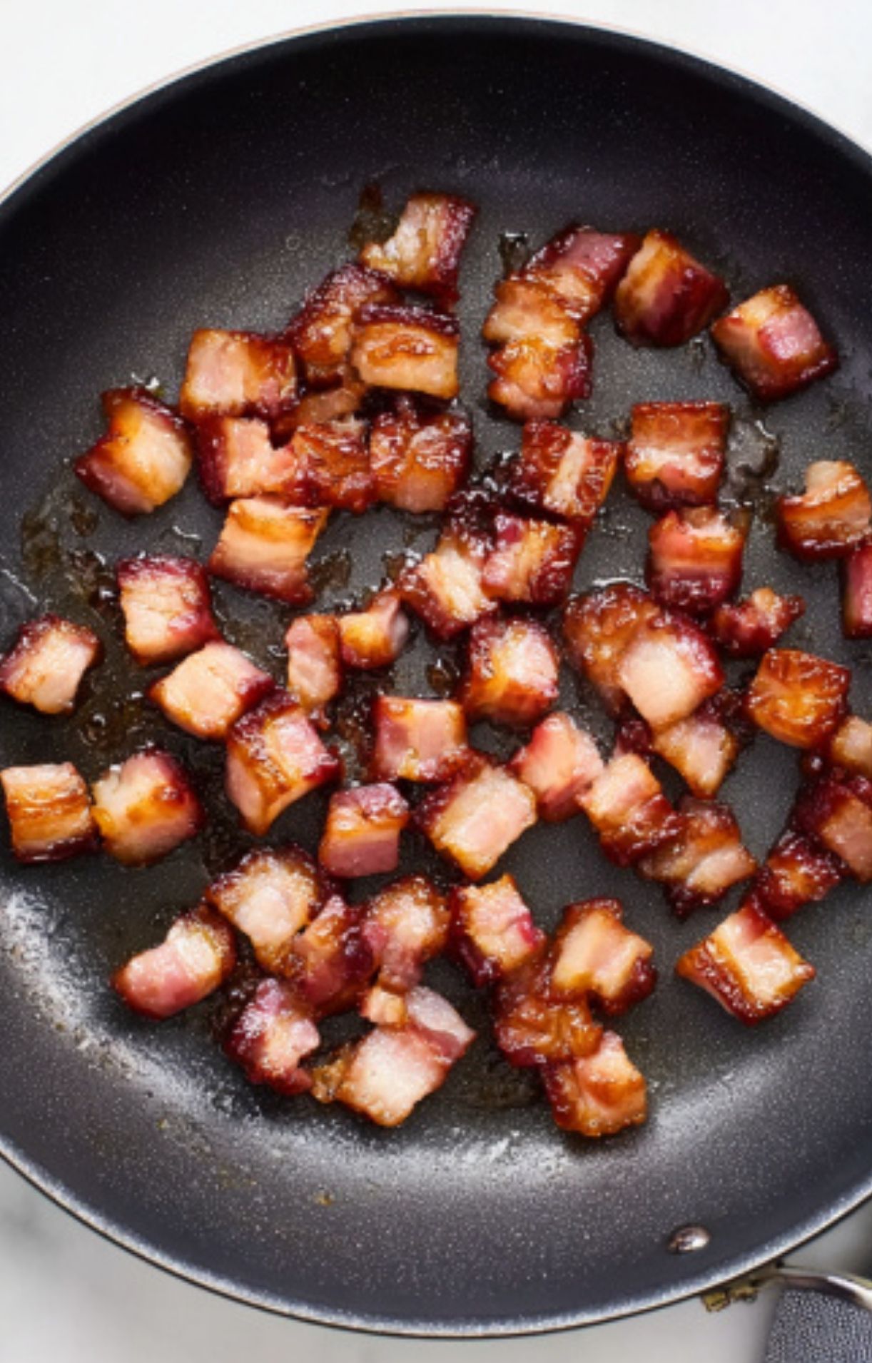 Cubes of thick-cut bacon frying in a pan, creating the rich, smoky base for this easy cassoulet recipe.