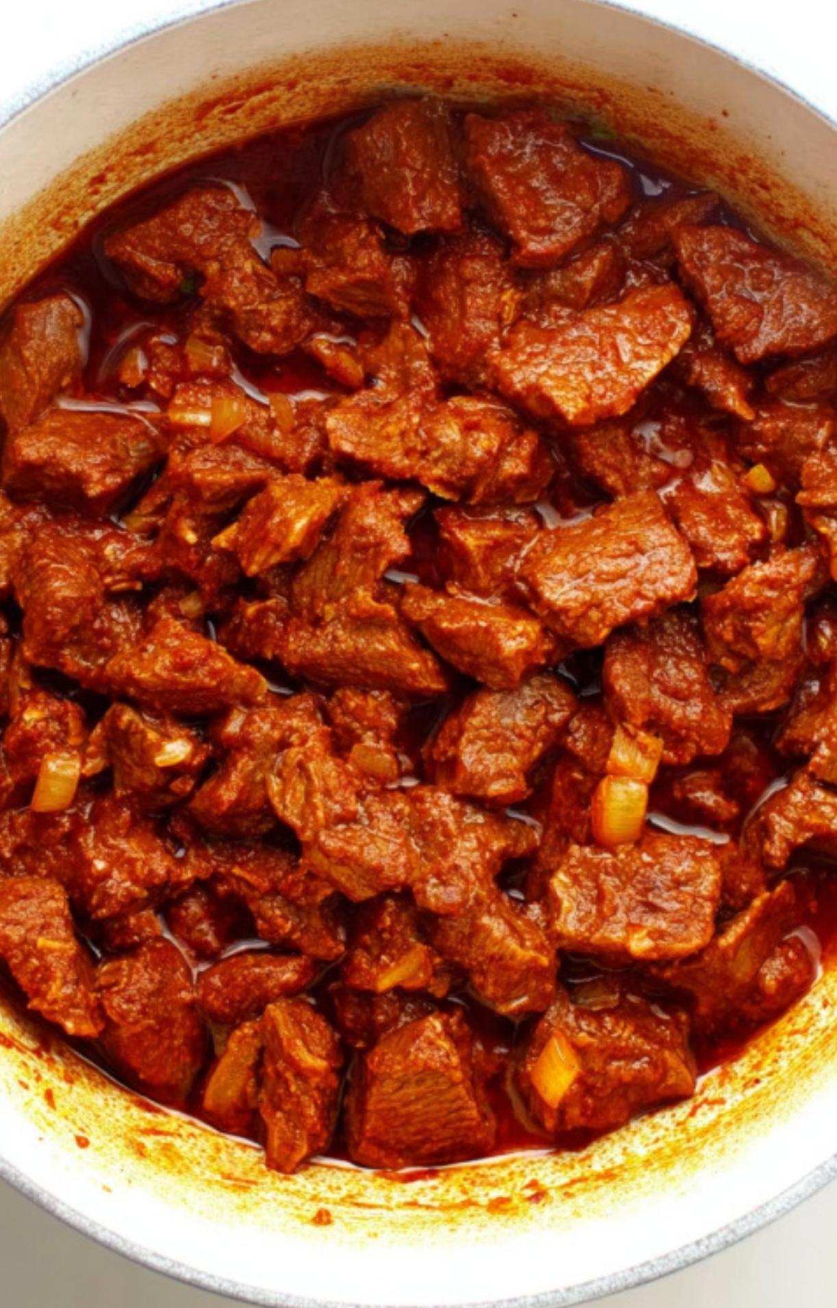 Large chunks of beef being seared with onions and paprika in a pot, creating a deep red color for the Hungarian Goulash Recipe.