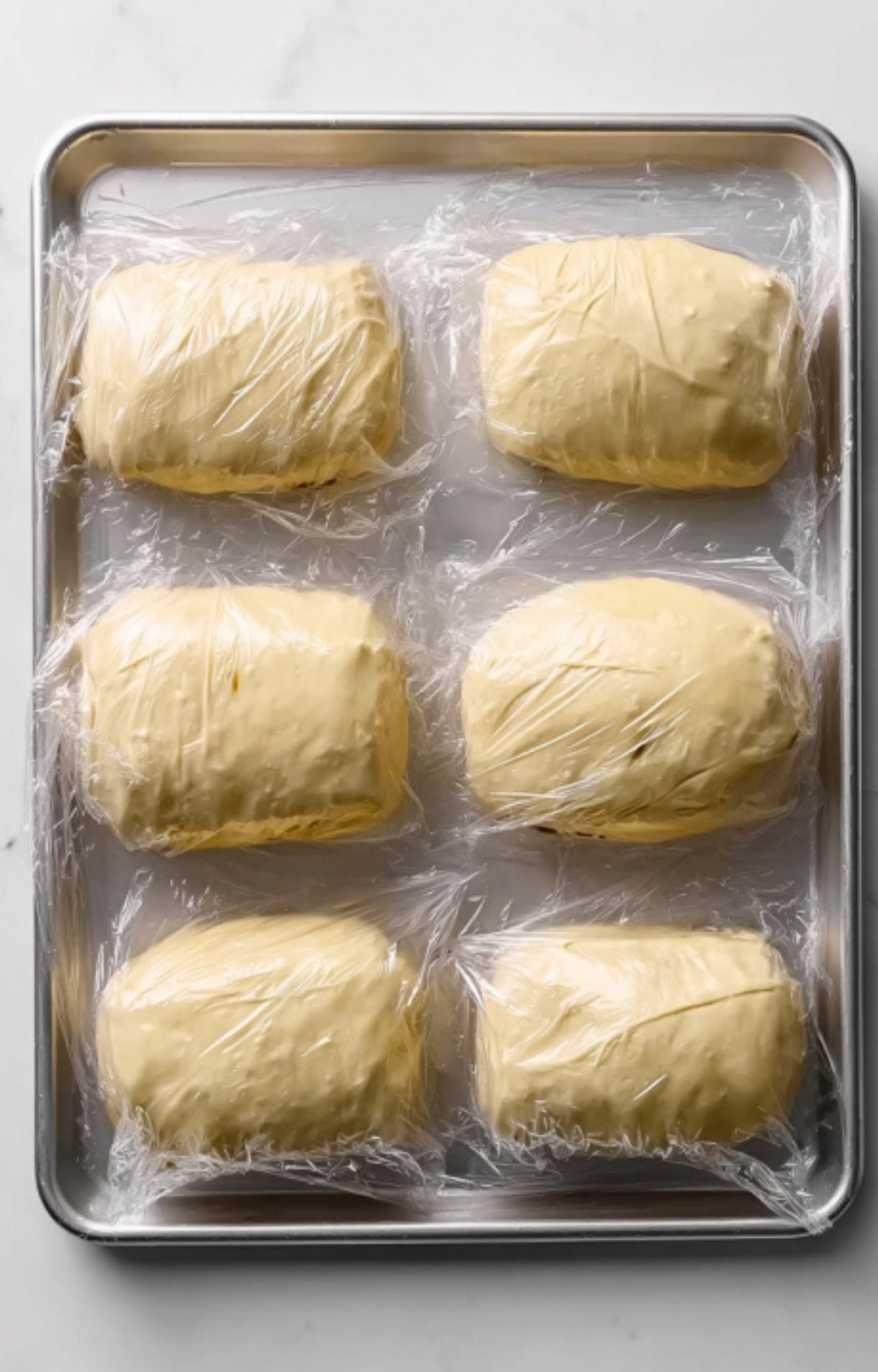 Unbaked beef wellingtons wrapped in puff pastry and chilled on a tray, ready to bake for stress-free holiday entertaining, dinner parties, or make-ahead meals.