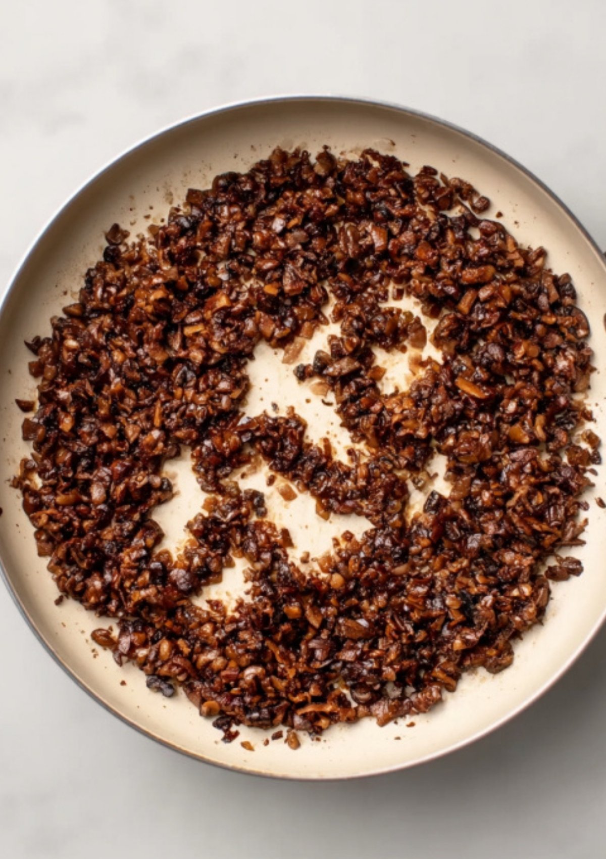 Mushroom duxelles mixture sautéing in a pan, a classic filling for gluten free and dairy free beef wellington recipes.