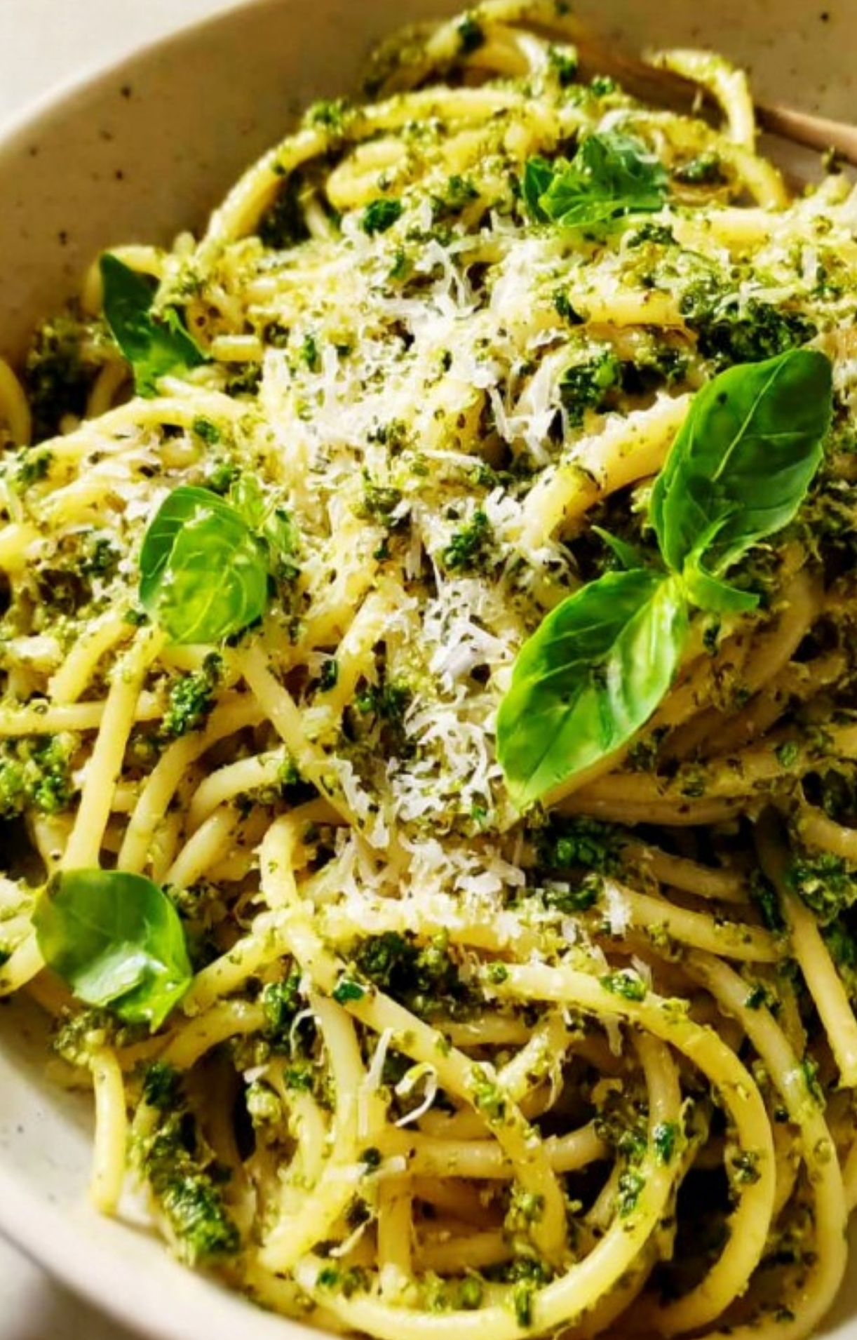 Bowl of spaghetti with homemade pesto, grated parmesan, and fresh basil, ideal for family week night dinners, healthy pasta recipes, and simple vegetarian meals.