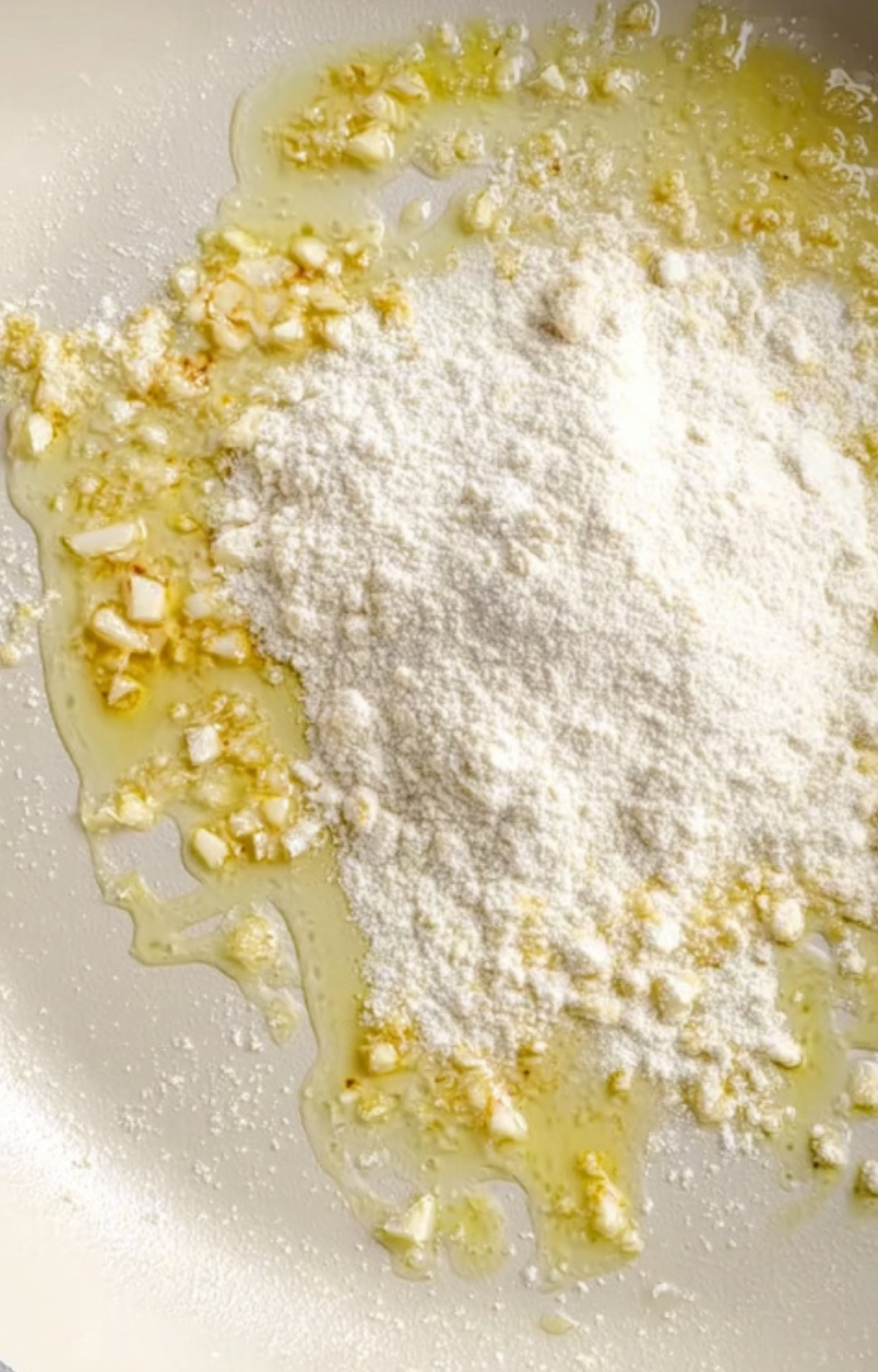 Flour poured into a skillet with sizzling garlic to begin building the Salisbury steak gravy.