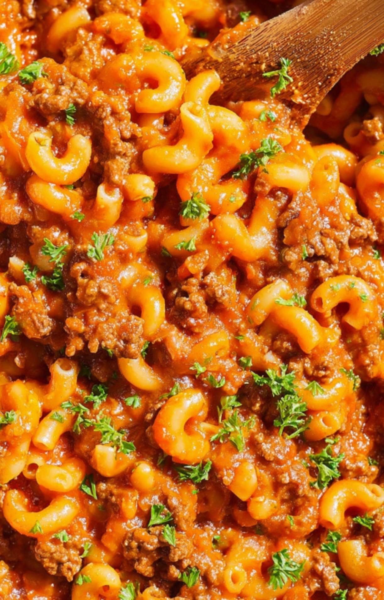 Close-up of cheesy American goulash with ground beef, elbow macaroni, and tomato sauce, topped with parsley. Classic one-pot family dinner, perfect for cozy fall and winter nights.