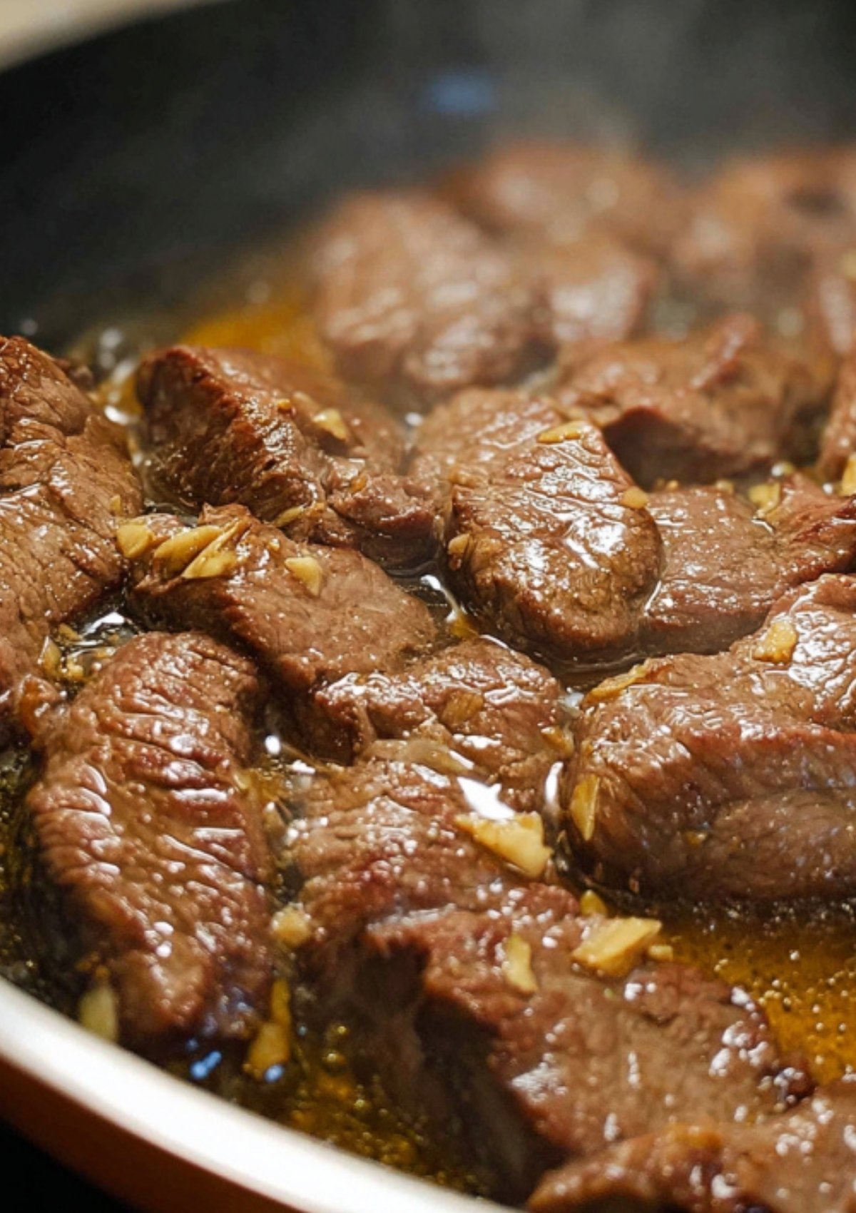 Beef slices cooking in a skillet with garlic and marinade for Beef Steak Filipino.