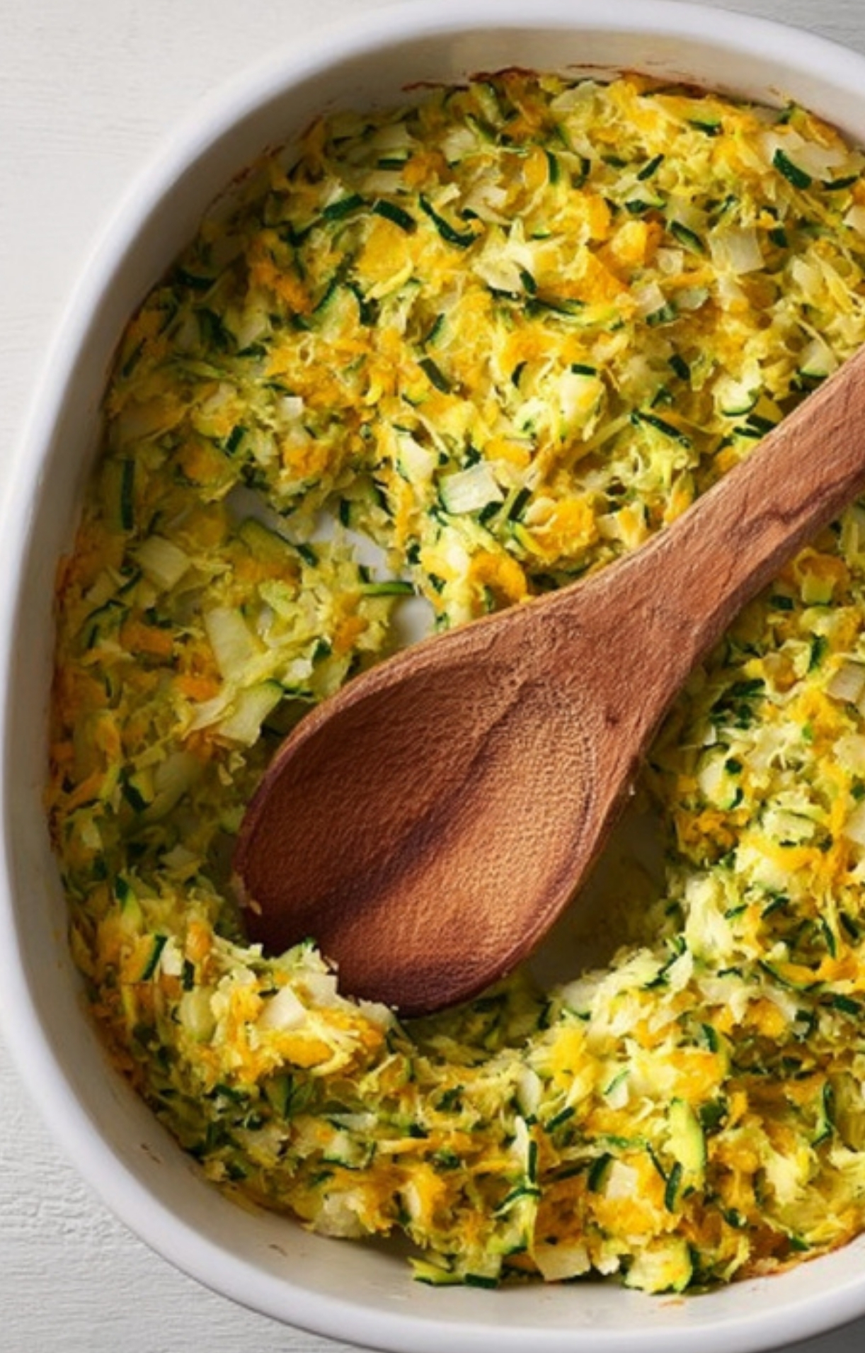 Shredded zucchini mixed with cheese and pressed into a casserole dish for a golden, gluten-free base