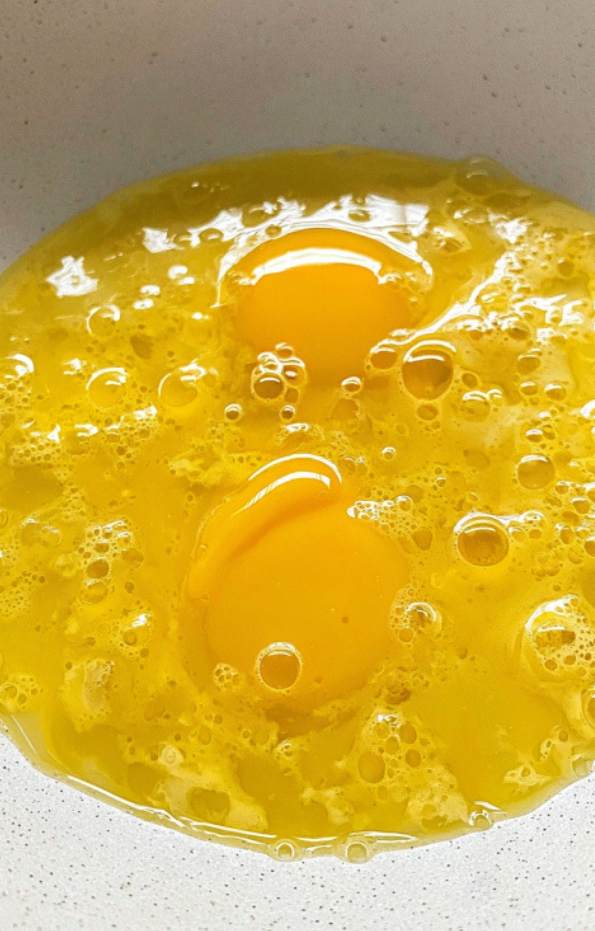 Two cracked eggs in a bowl, perfect for making creamy scrambled eggs for breakfast.
