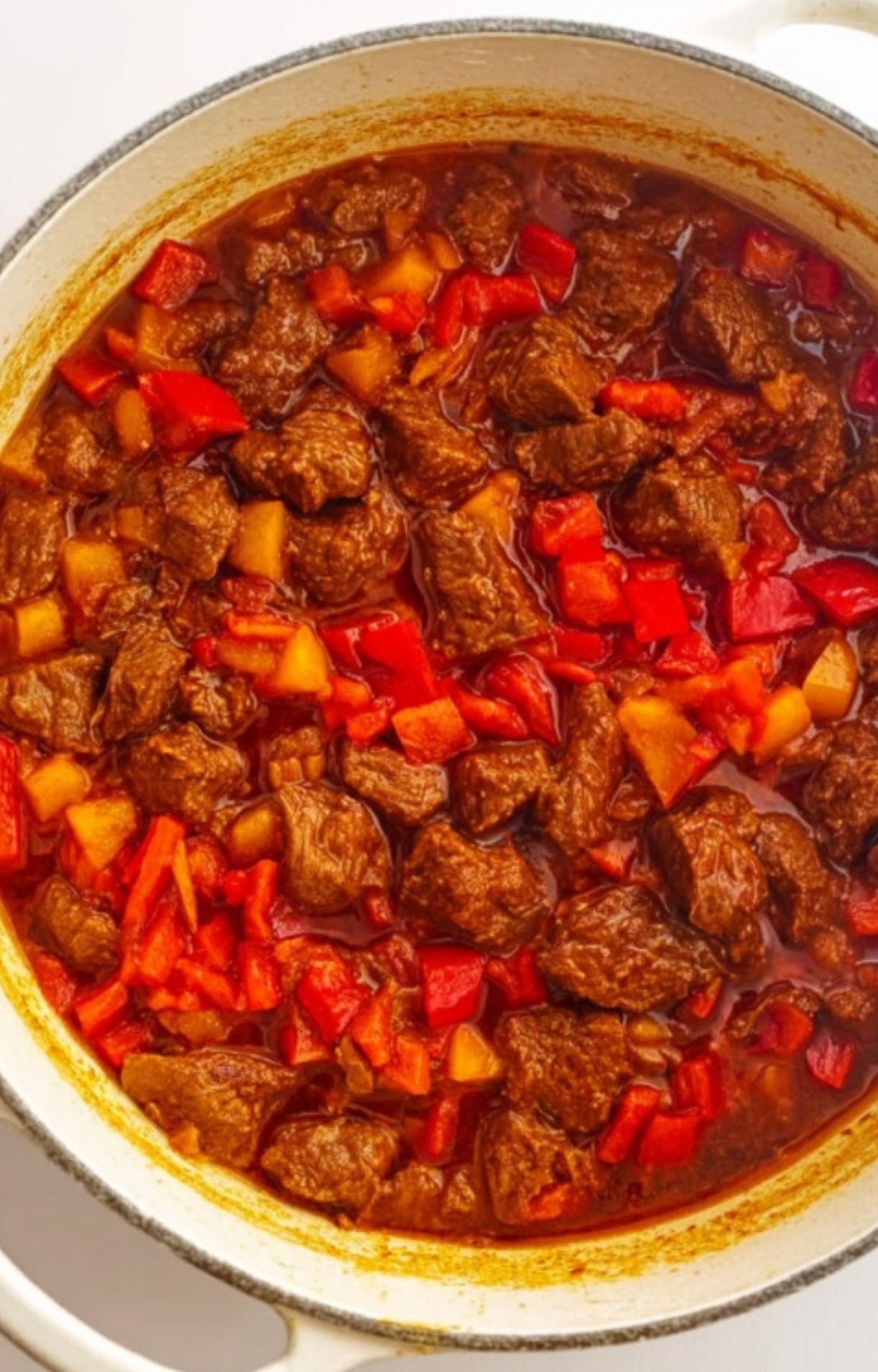 Tender beef chunks and bright red diced bell peppers simmering together in a savory sauce for a Hungarian Goulash Recipe.