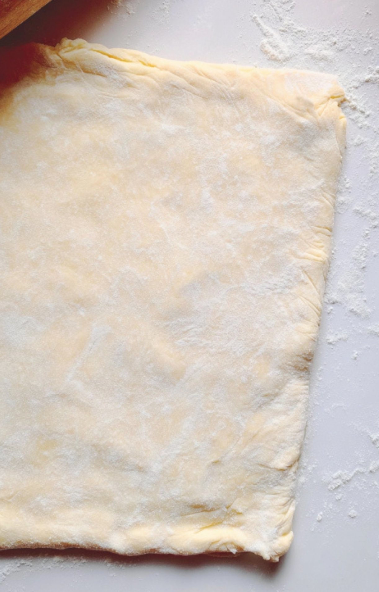 Homemade puff pastry rolled out and floured, perfect for wrapping Christmas Beef Wellington. Flaky pastry for holiday recipes.