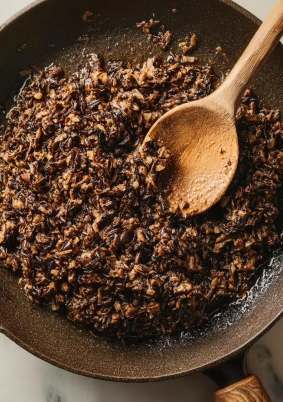Savory mushroom duxelles cooking in a skillet, ready to fill mini beef wellington appetizers for rich, classic flavor.