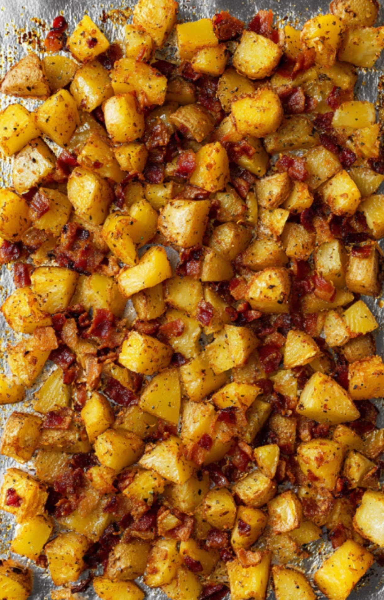 Golden roasted potatoes mixed with bacon pieces on a baking tray, perfect for a cheesy ranch potato casserole.