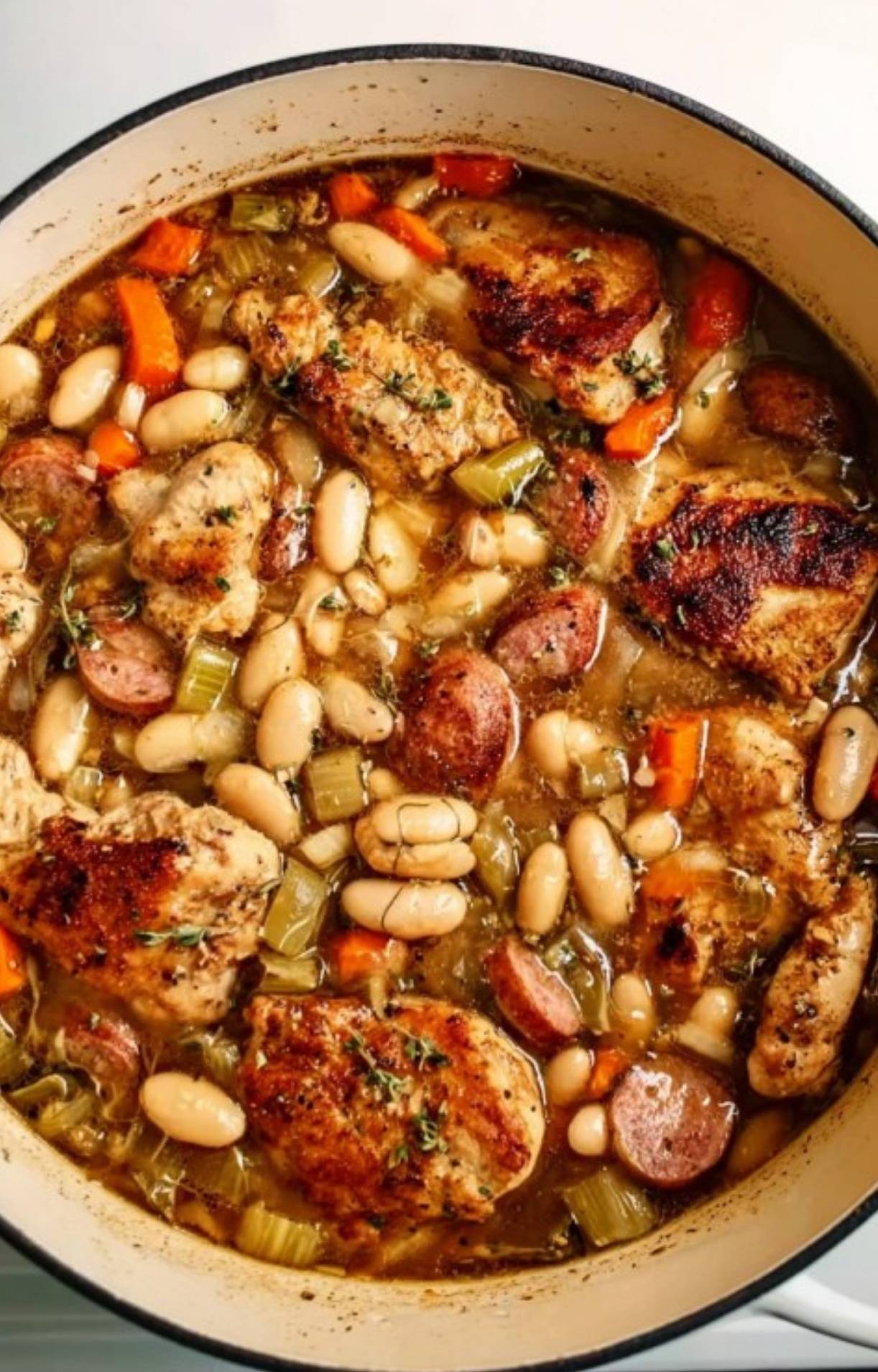 Simple Chicken Cassoulet in a Dutch oven with sausage, white beans, carrots, and celery, perfect for weeknight dinners.