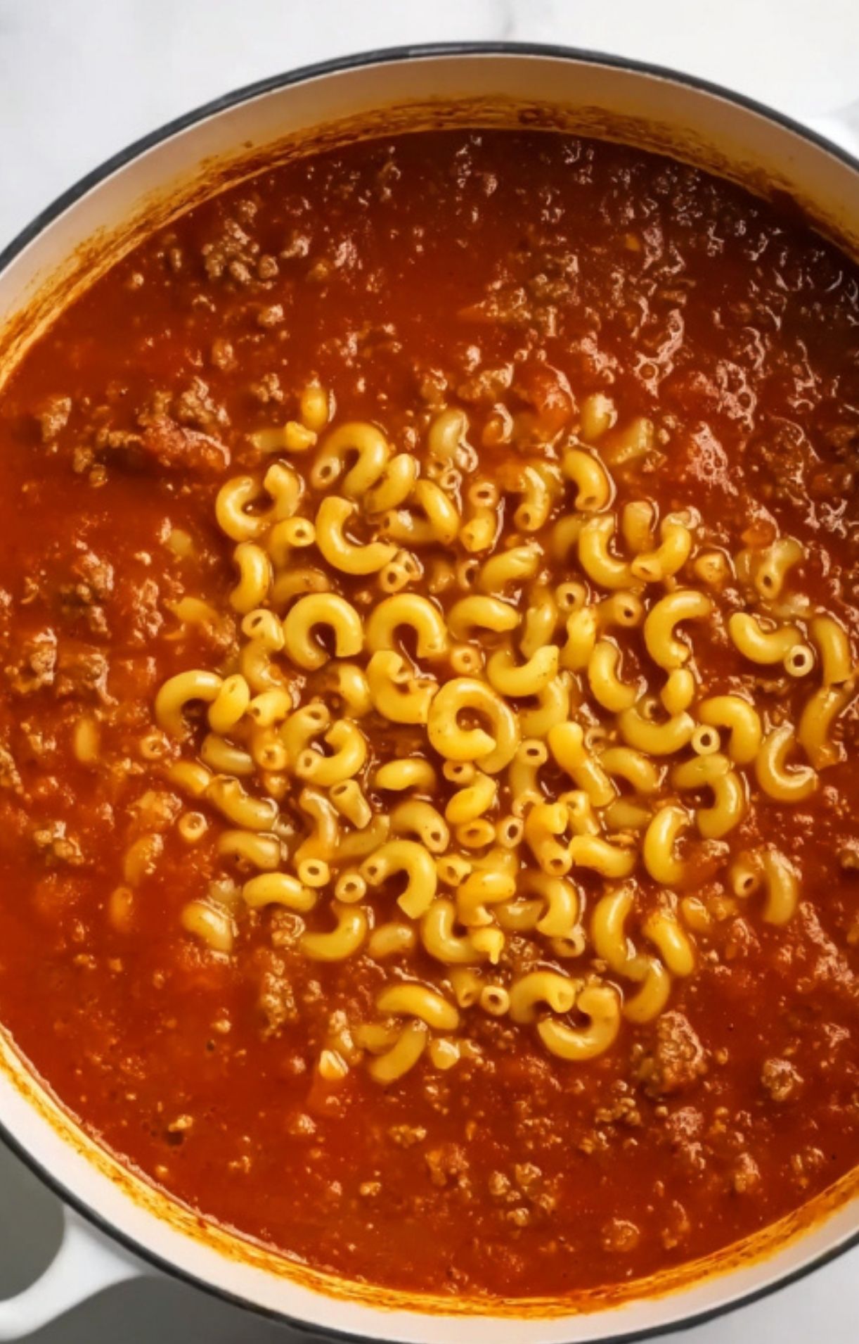 Pot with macaroni pasta added to thick beef and tomato sauce. Simple one pot meal for easy weeknight cooking and kid-approved dinners.