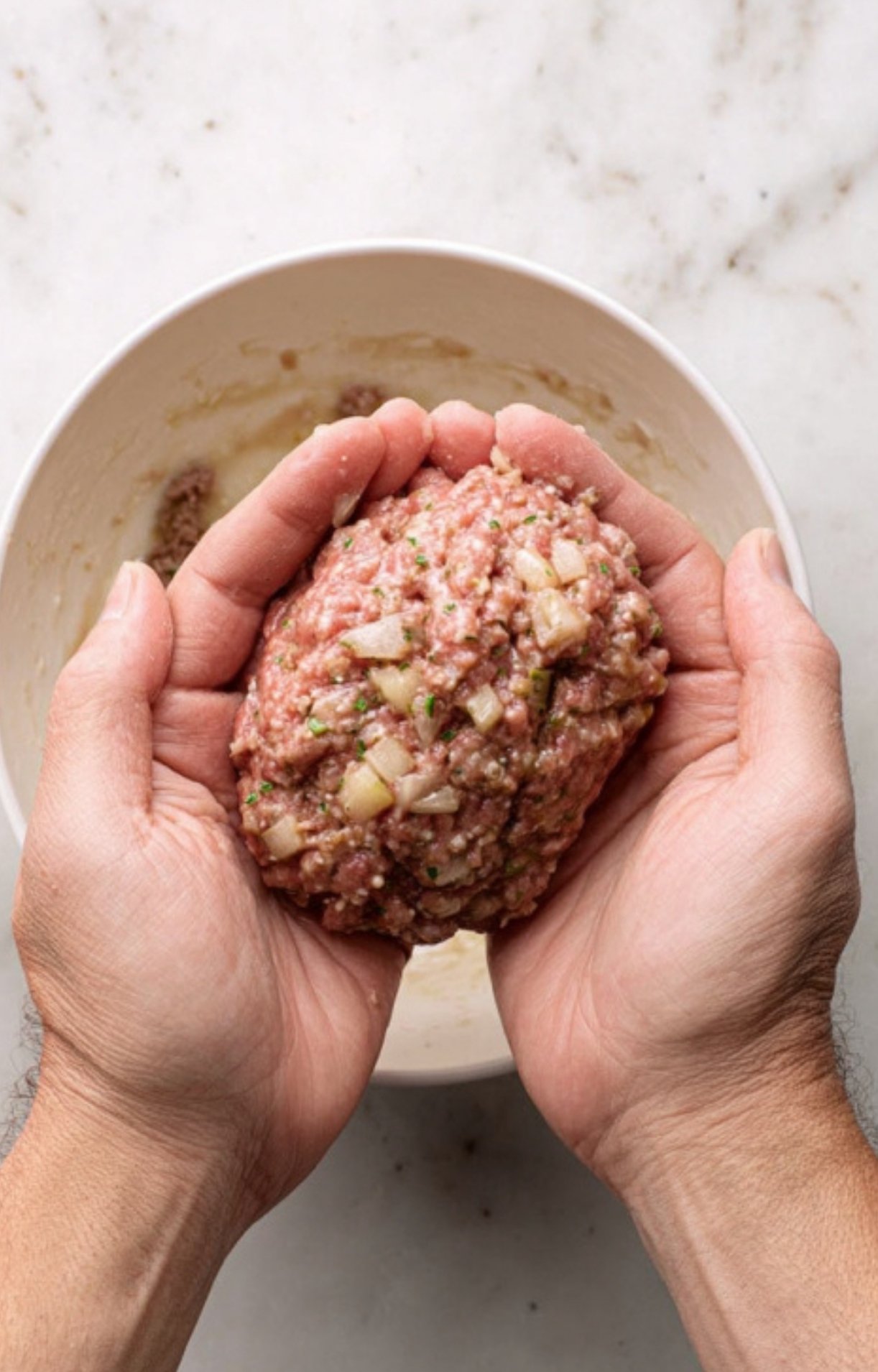 Hands shaping a seasoned ground beef mixture with onions, the flavorful filling for homemade beef Wellington.