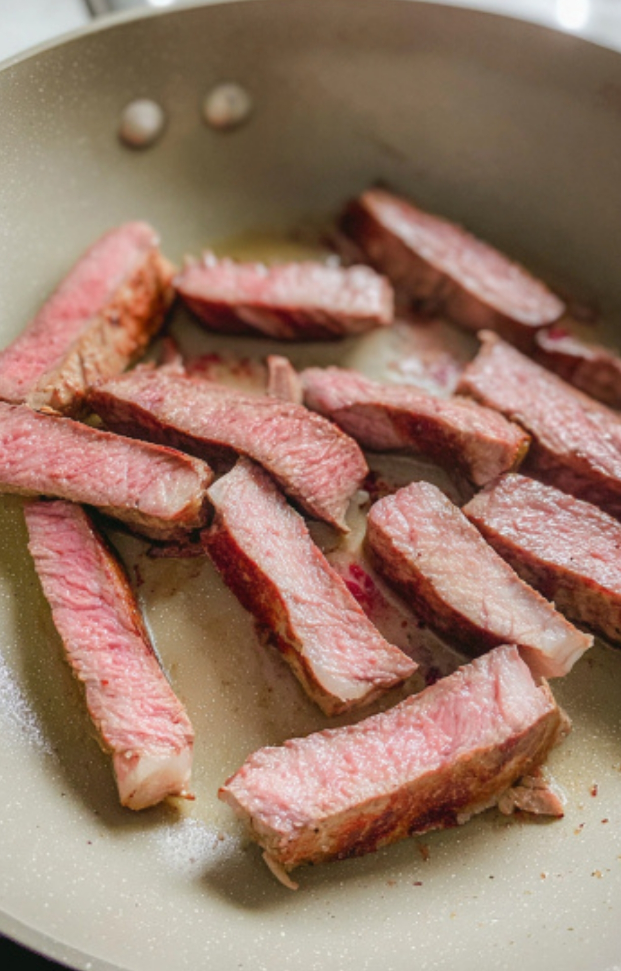 Tender leftover steak strips warming in a skillet for a quick protein breakfast.