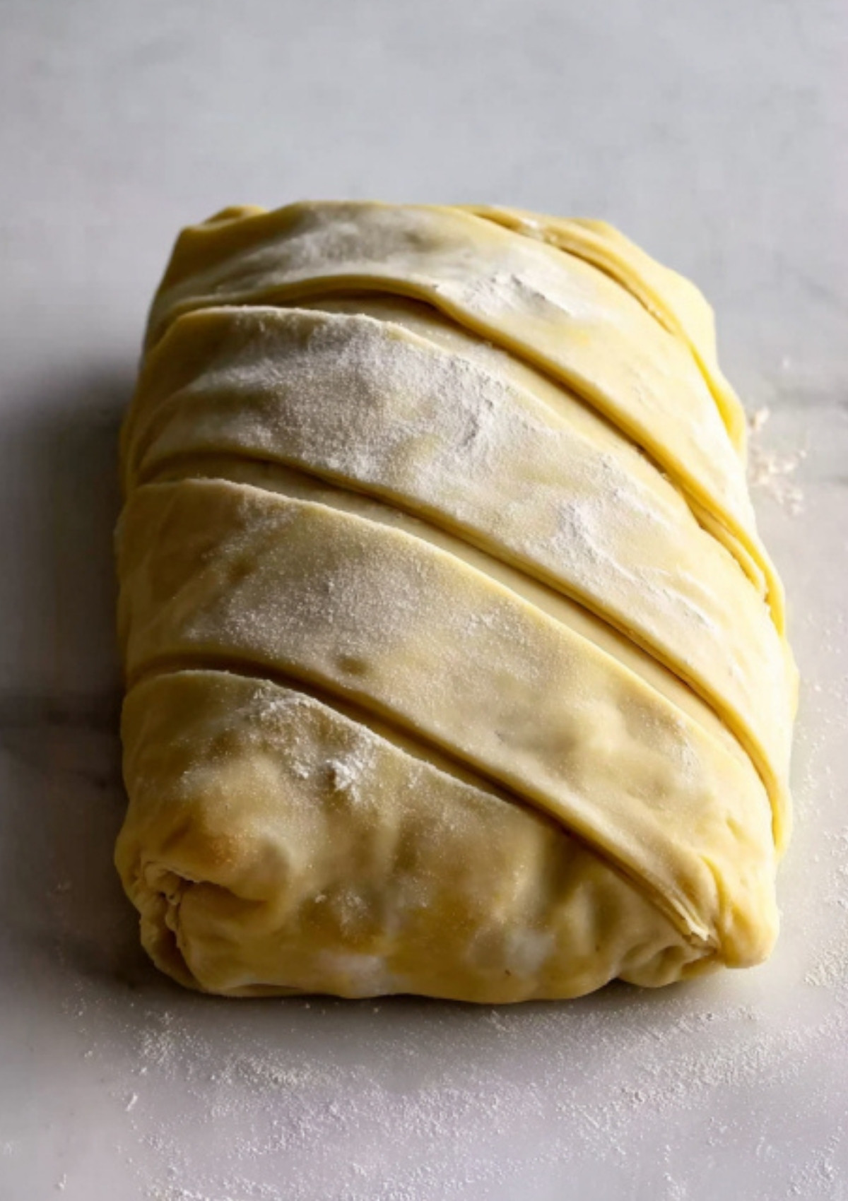 Unbaked beef wellington wrapped in puff pastry, scored and dusted with flour, prepped for baking as an elegant dinner for special events.