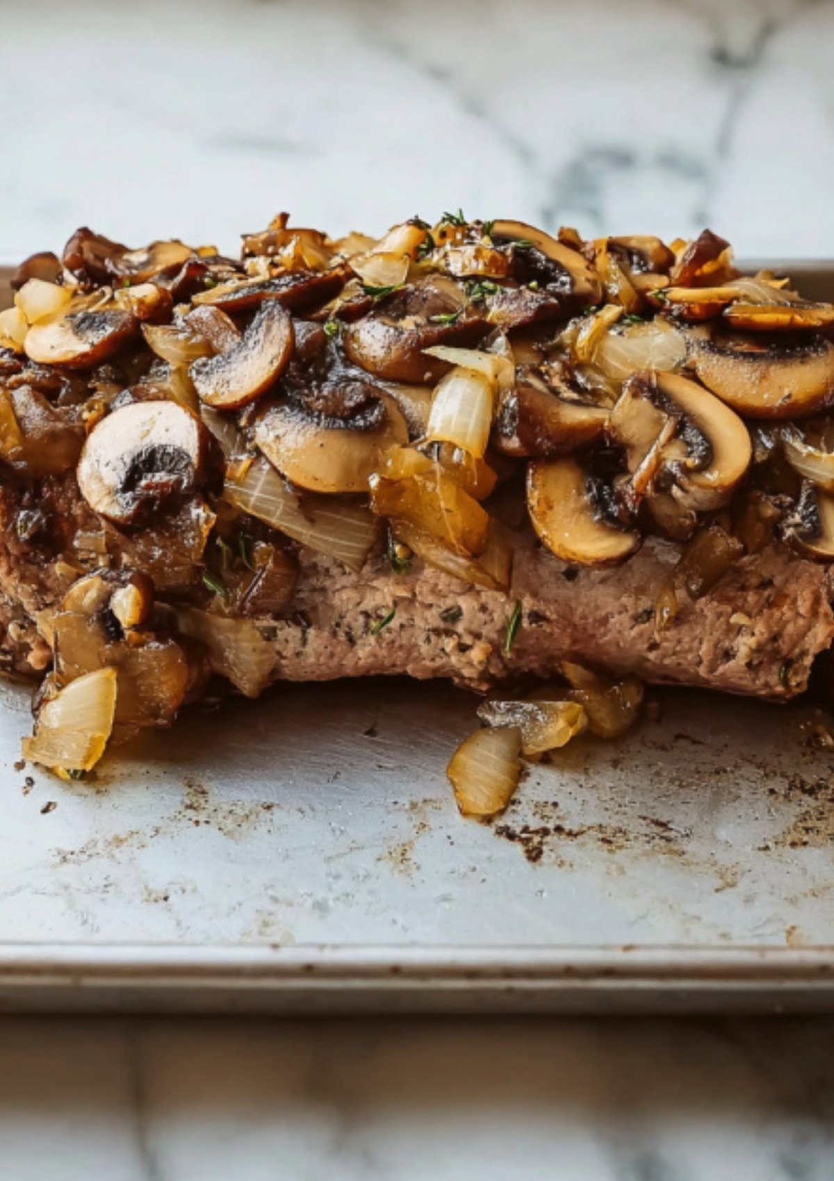 Beef tenderloin topped with sautéed mushrooms and onions, showing the step before wrapping in pastry for an easy beef wellington.